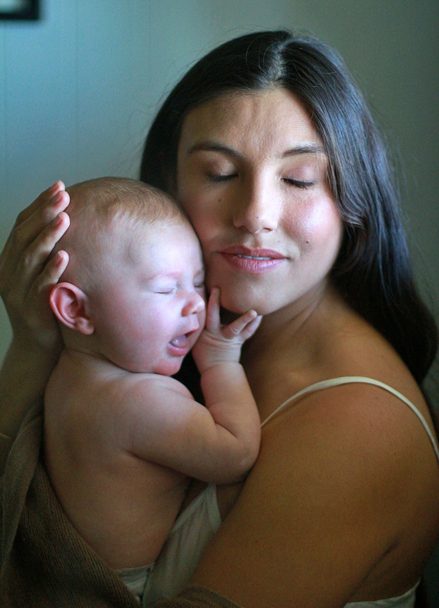 Intimate motherhood moment of a mum cuddling her baby at home by A Lasting Impression Photography.