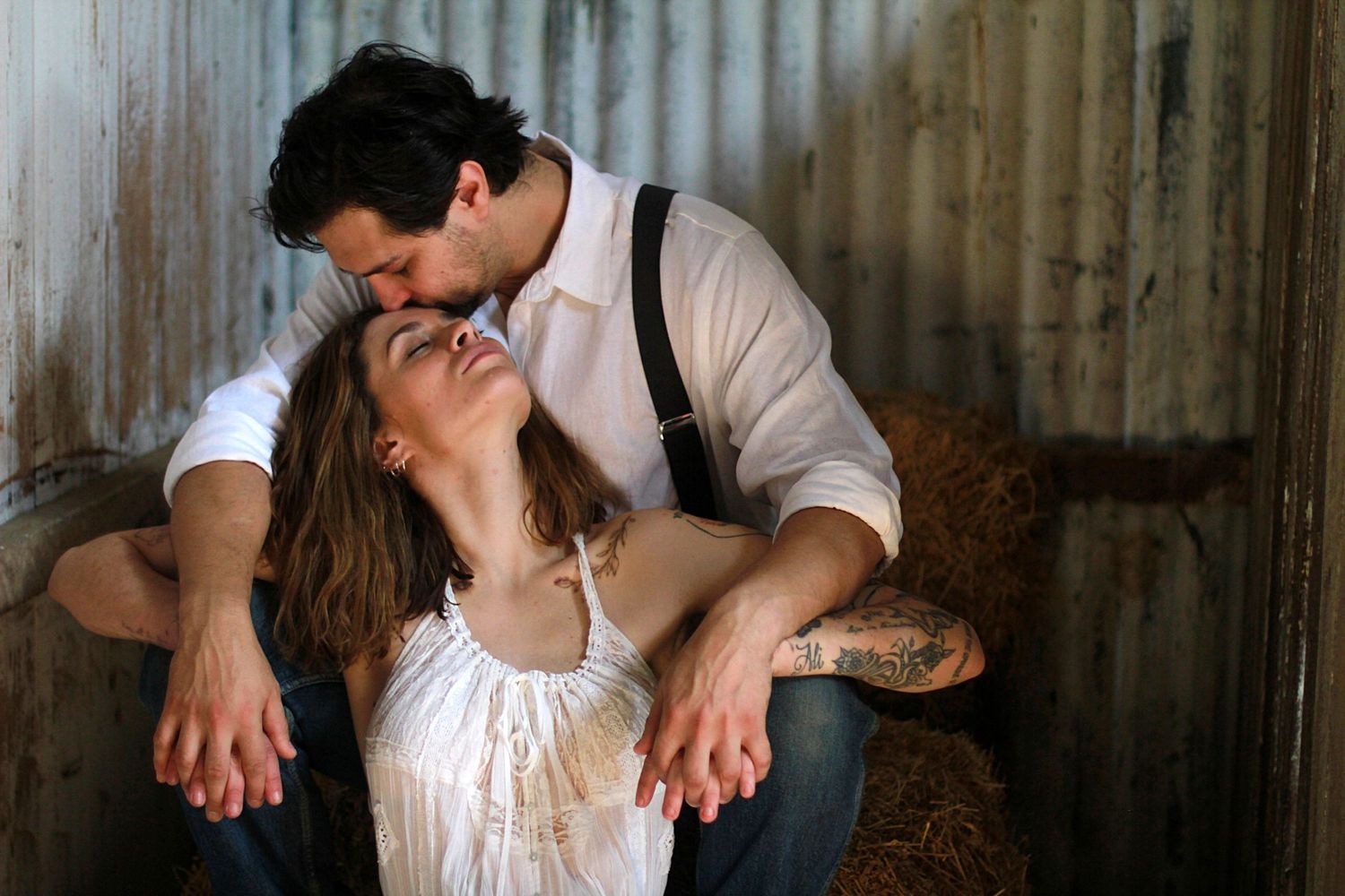 Cozy barn engagement portraits with hay bales and warm country charm
