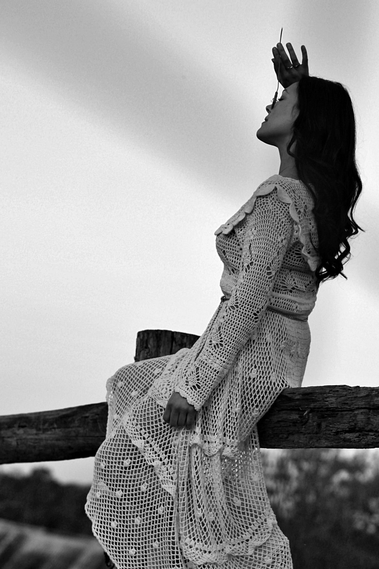 Woman sitting on a fence surrounded by nature in a rural setting