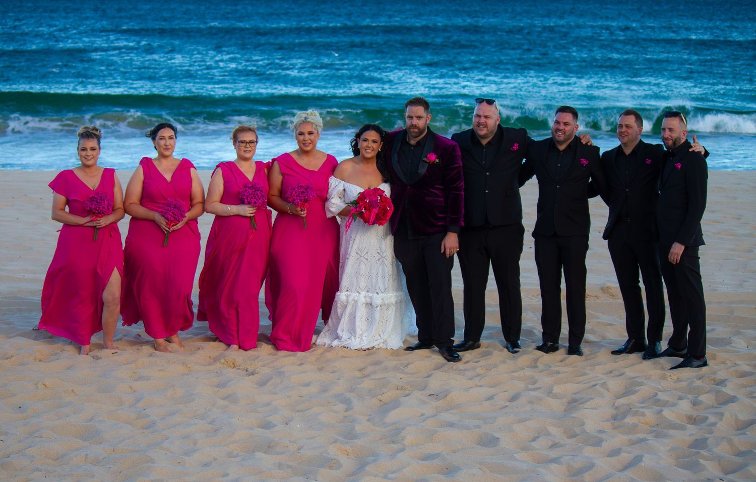Full bridal party portrait with bridesmaids, groomsmen, bride and groom celebrating together during an Illawarra beach wedding.