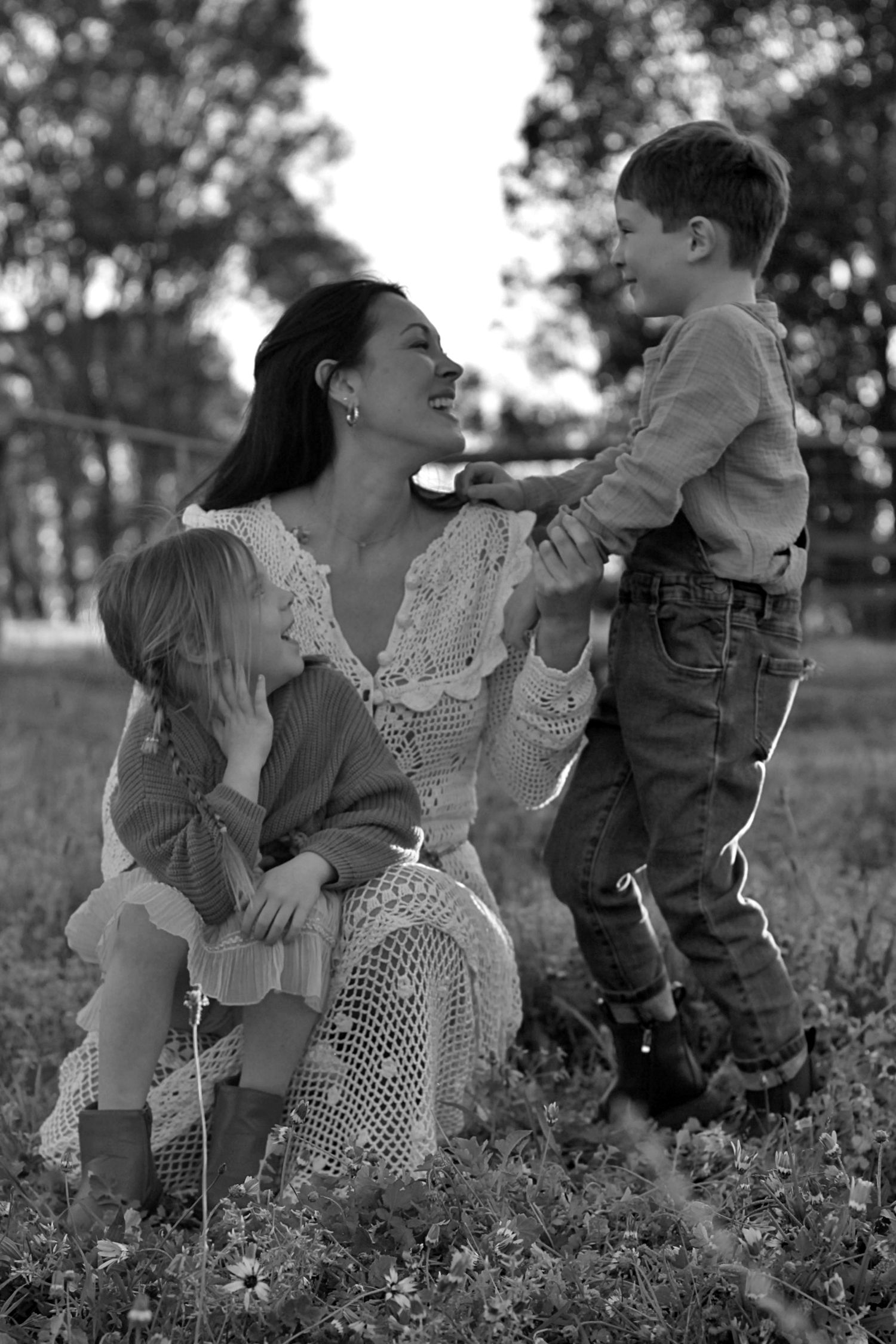 Playful family photo of mum and children sitting together outdoors during a family session
