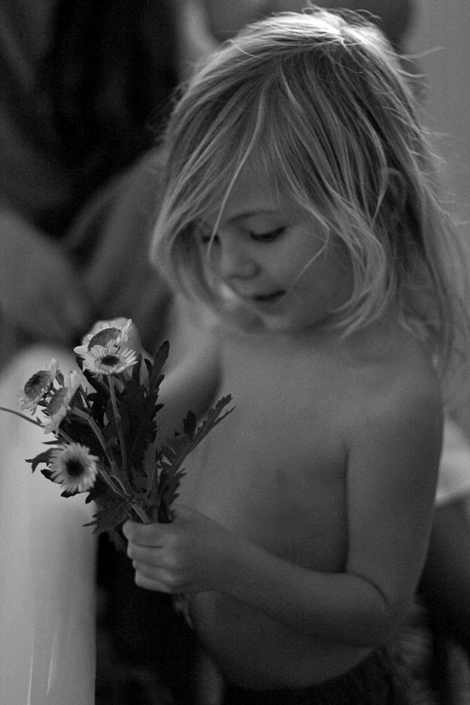 Candid moment of a young boy picking flowers to put in a bath during lifestyle motherhood session.
