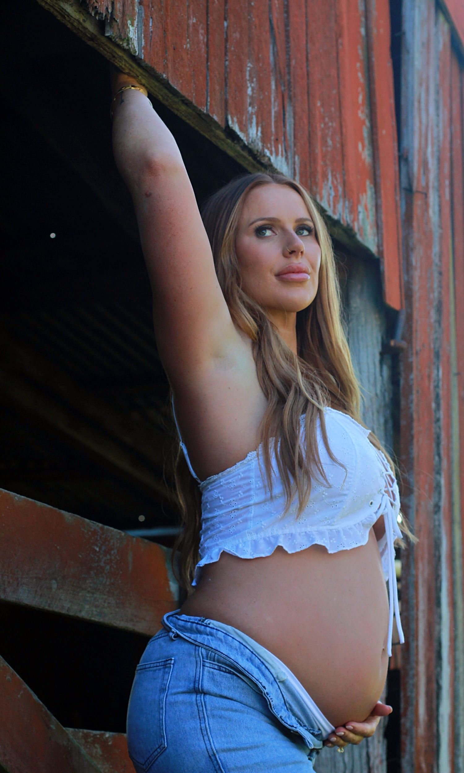 Expectant mother enjoying a natural maternity photoshoot by a barn by A Lasting Impression Photography.