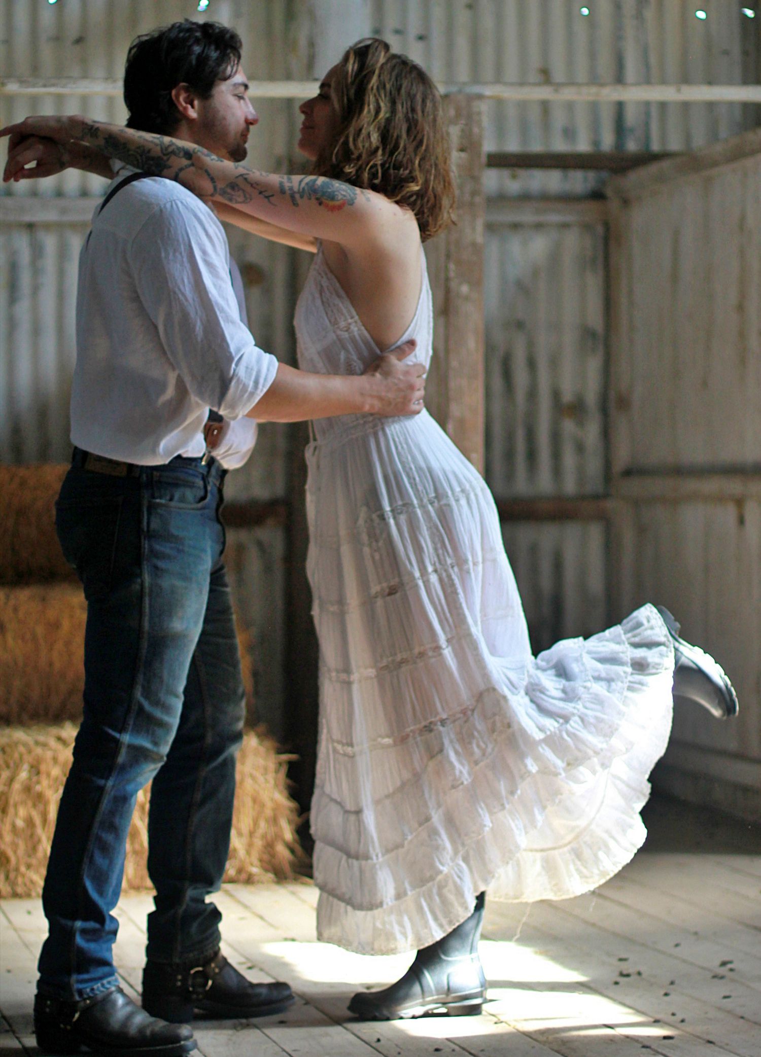 Romantic engagement photos of a couple dancing together inside a rustic barn