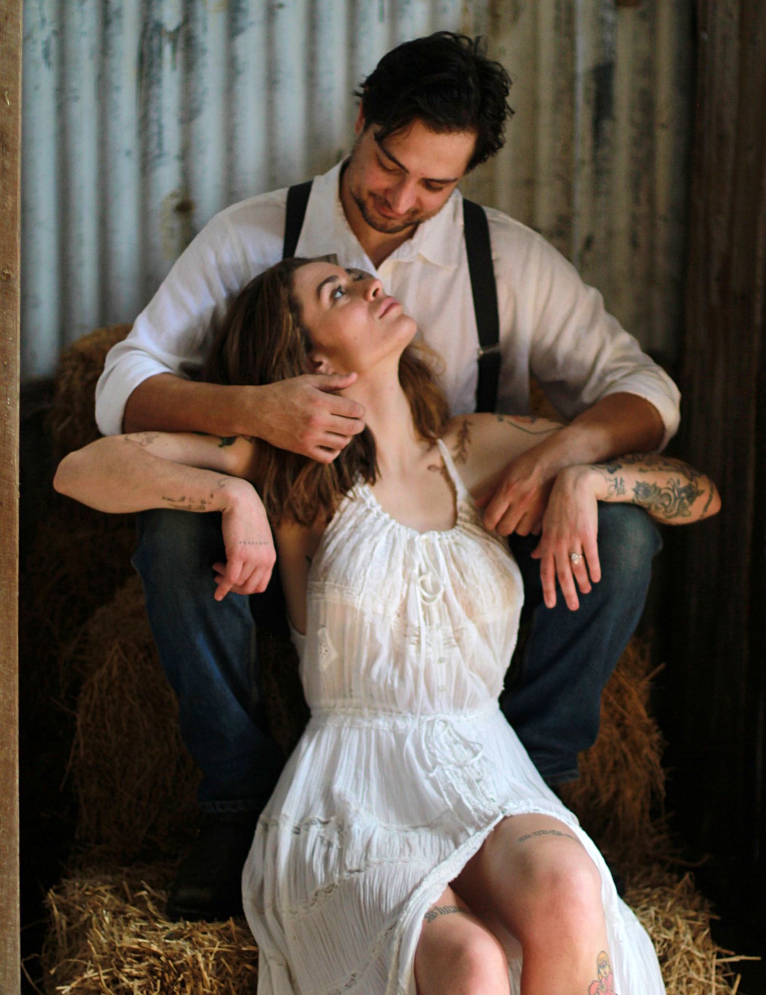 Cozy barn engagement portraits with hay bales and warm country charm