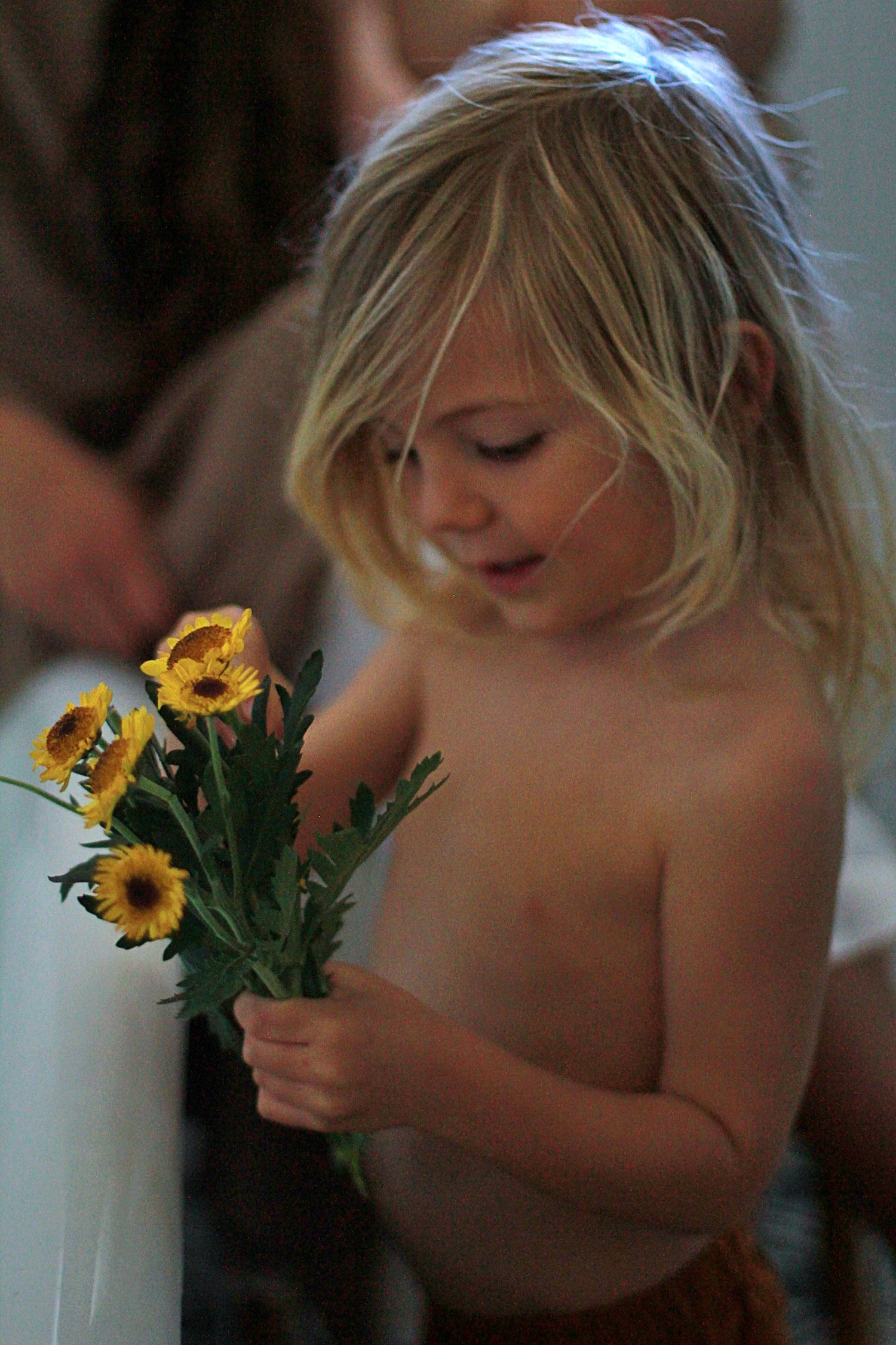 Candid moment of a young boy picking flowers to put in a bath during lifestyle motherhood session.