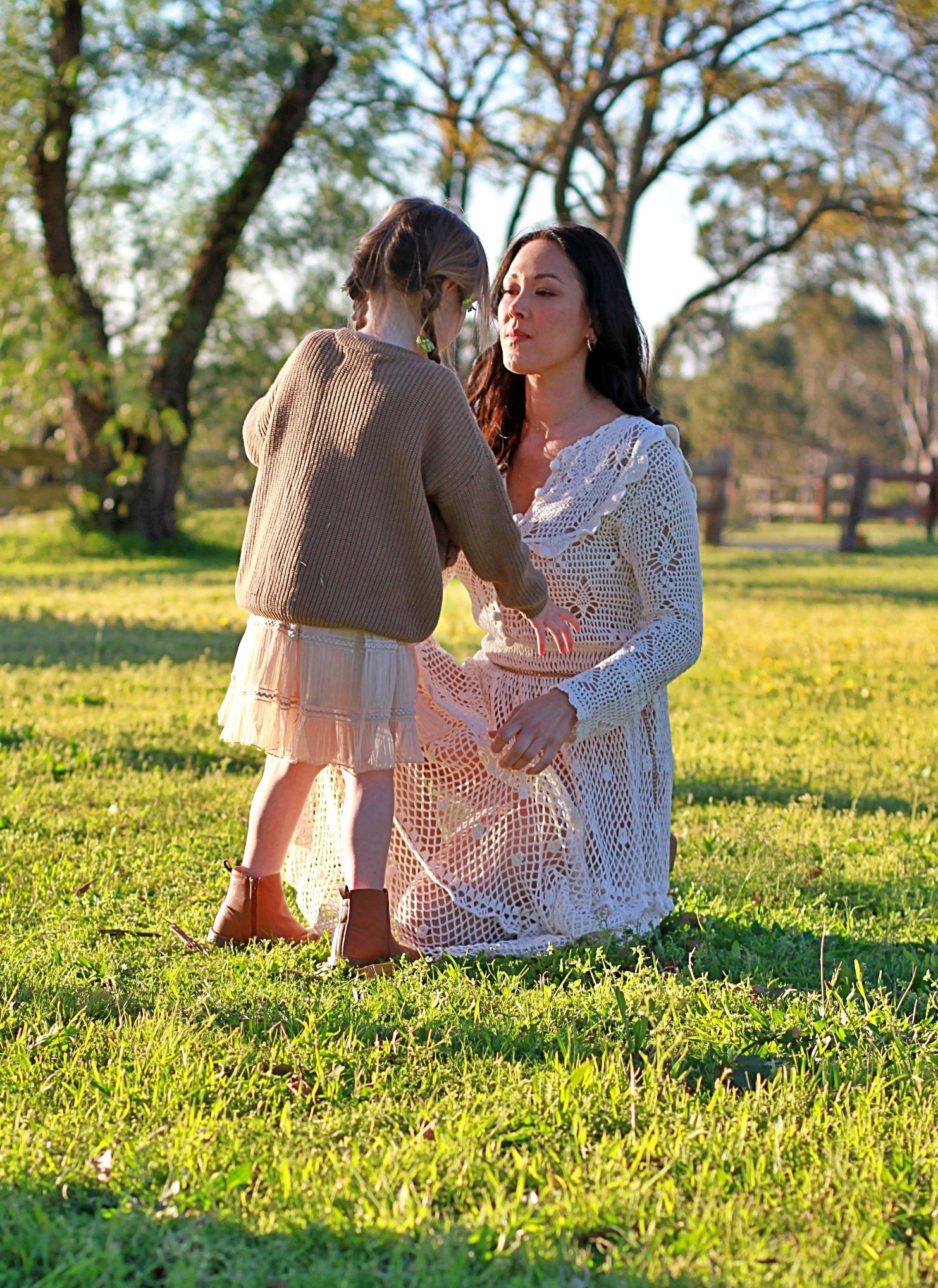 Mum kneeling to connect with her daughter during outdoor family session