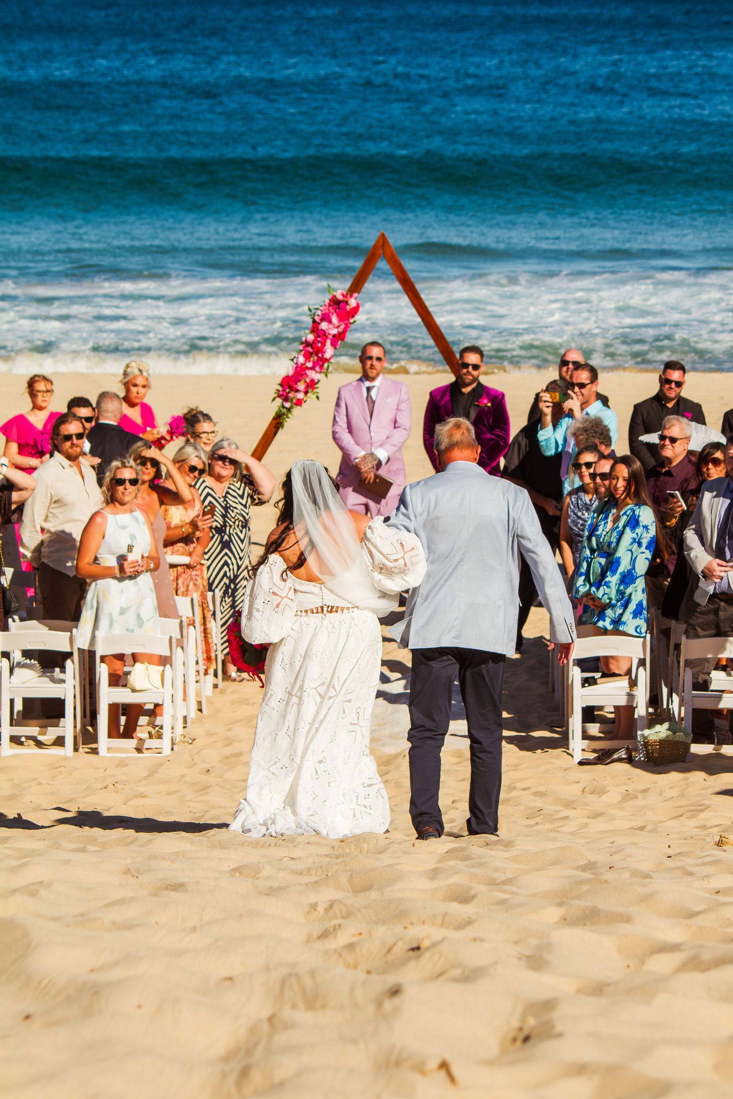 Behind view of the bride walking down the aisle with her father at an Illawarra beach wedding ceremony.