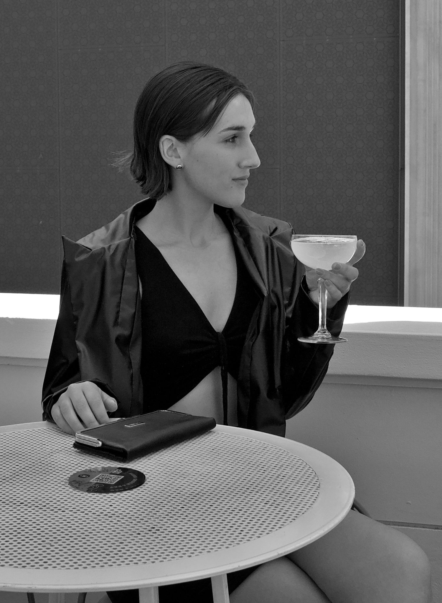 Stylish woman enjoying a margarita at a table, looking thoughtfully into the distance during a lifestyle content shoot in Wollongong.
