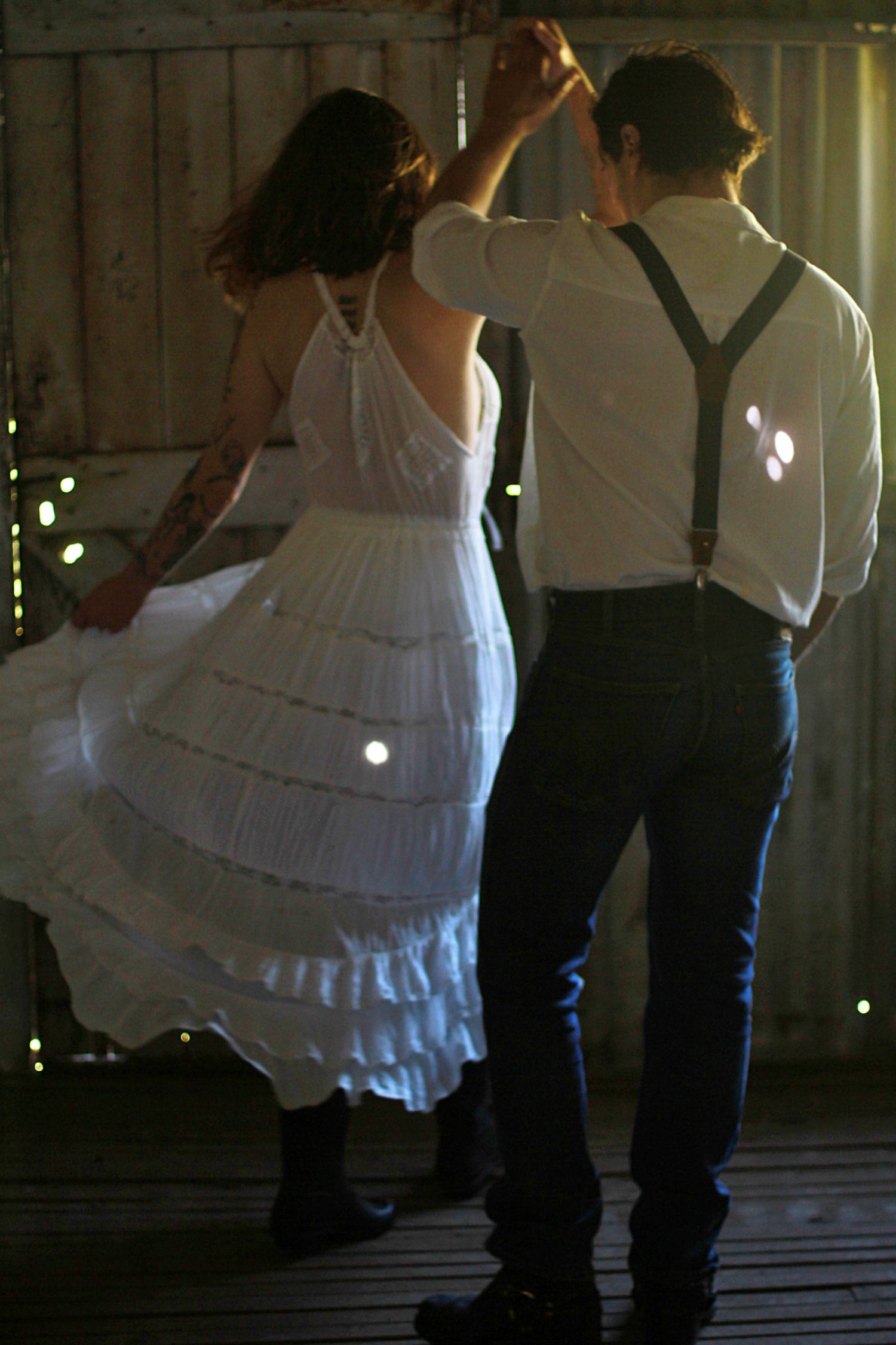 Romantic engagement photos of a couple dancing together inside a rustic barn
