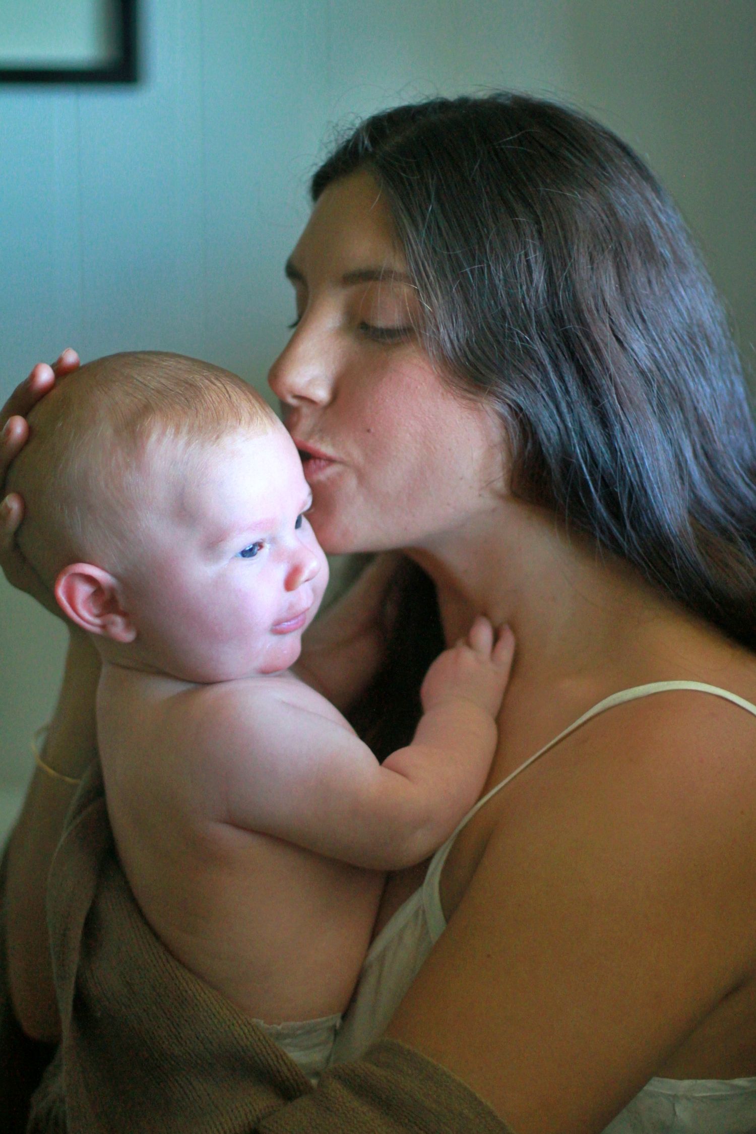 Portrait of mum kissing her newborn baby during a lifestyle motherhood session by A Lasting Impression Photography.