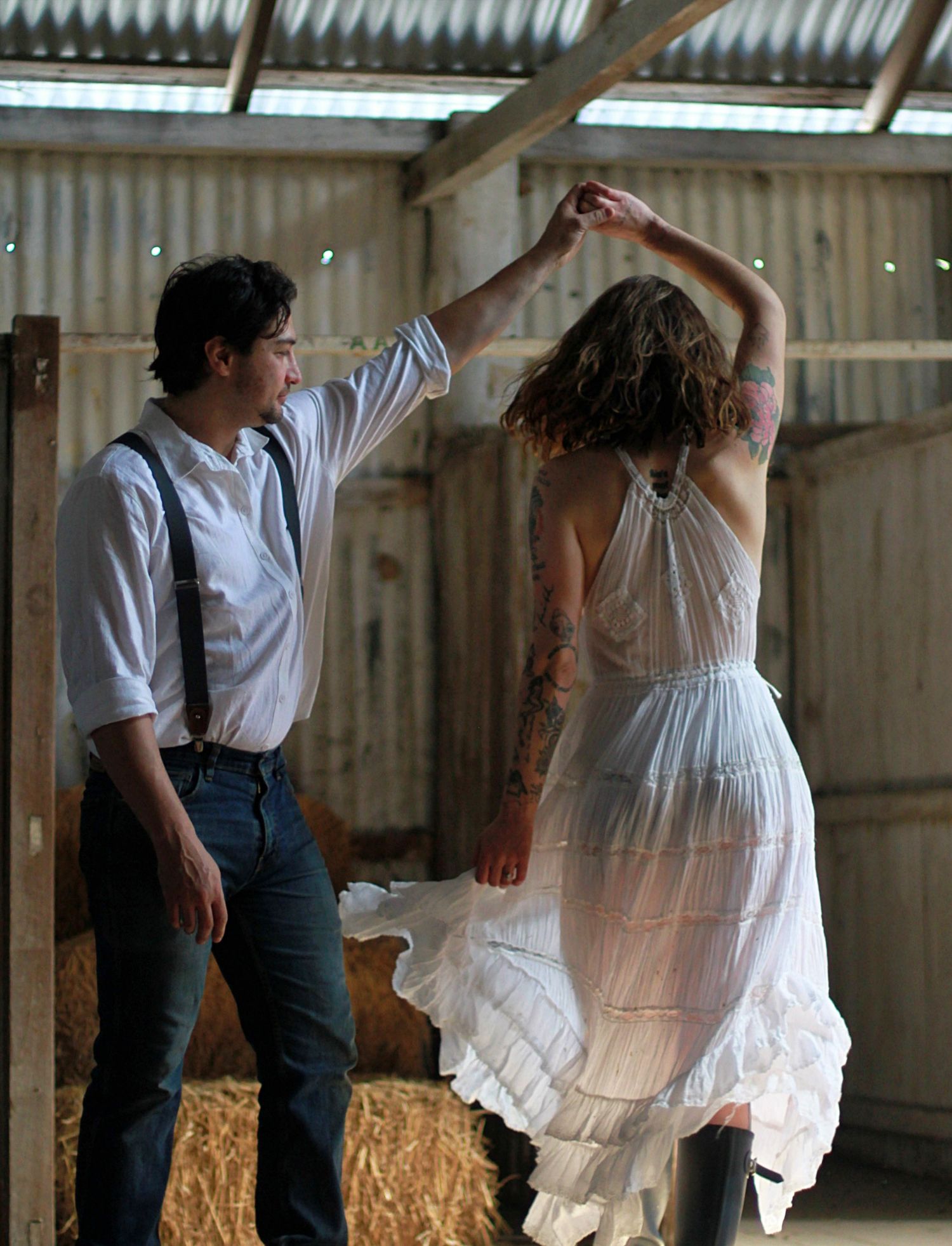 Romantic engagement photos of a couple dancing together inside a rustic barn
