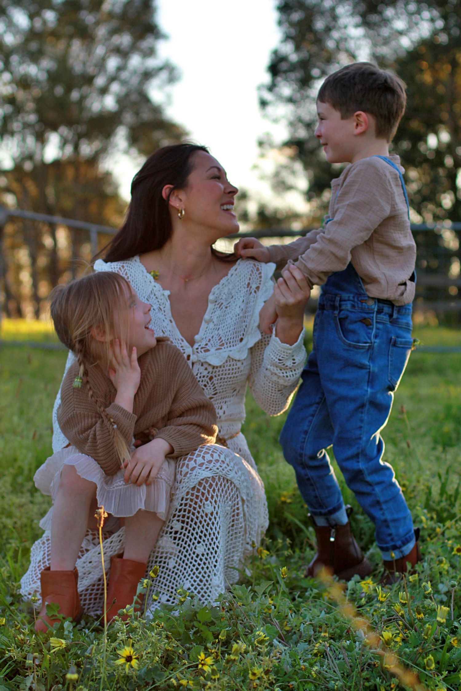 Playful family photo of mum and children sitting together outdoors during a family session