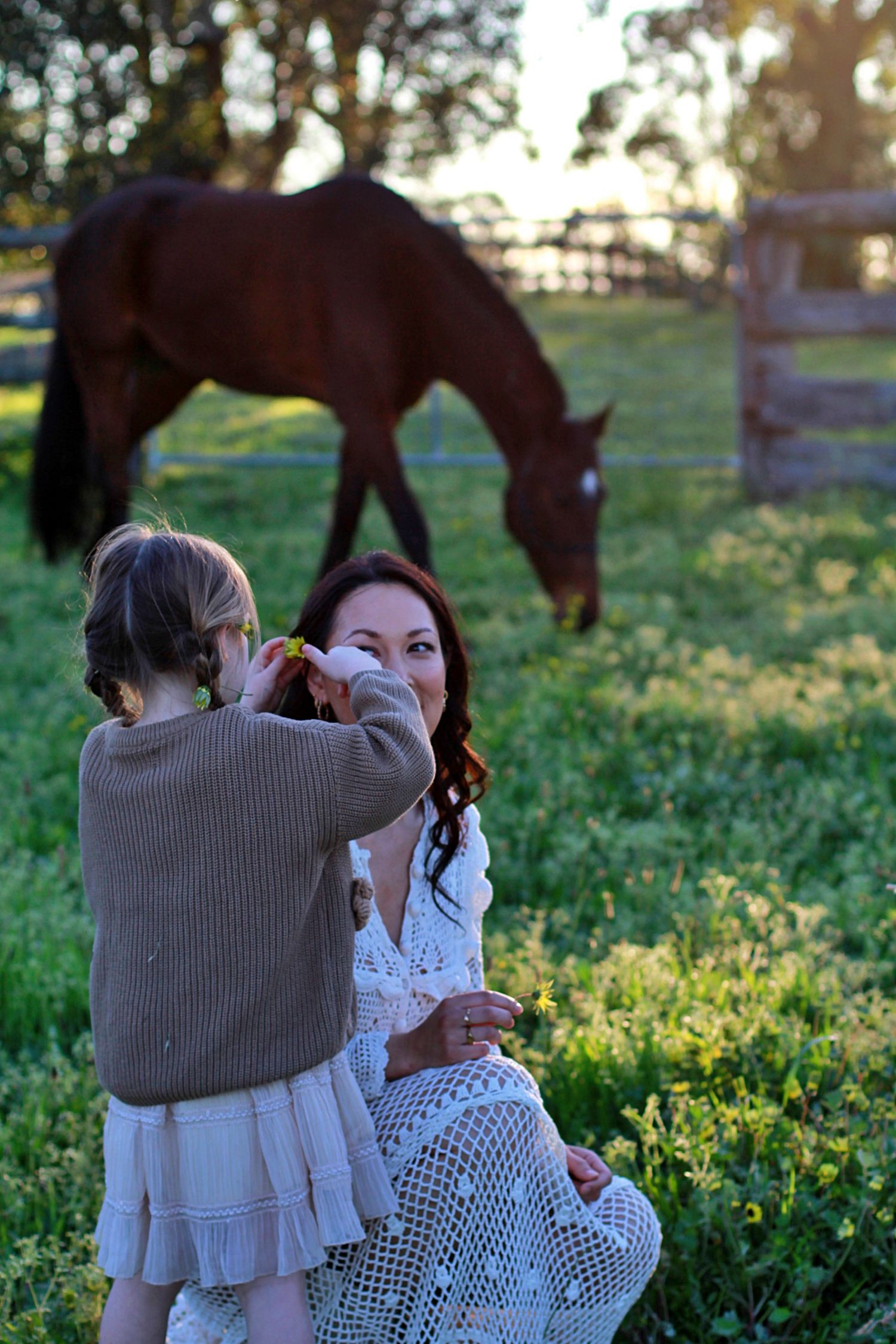 Sweet moment of daughter decorating mum’s hair with flowers during a family session