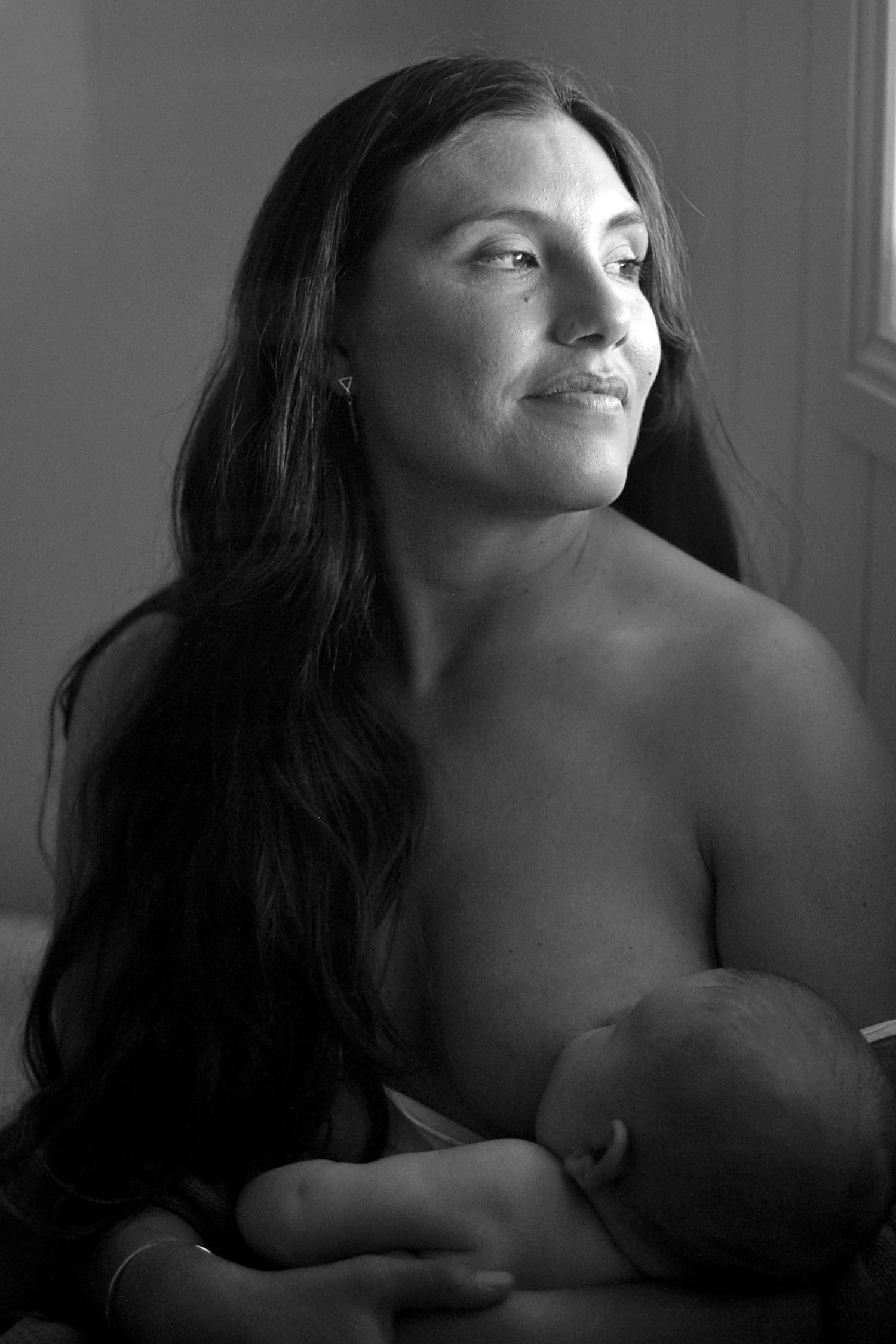 Mother breastfeeding her baby during a natural lifestyle motherhood session at home by A Lasting Impression Photography.