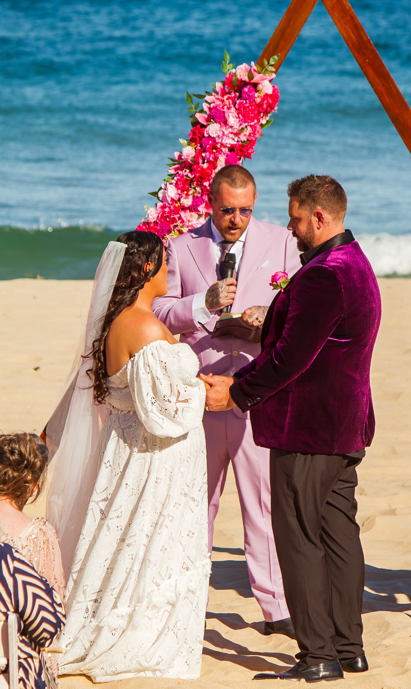 Bride and groom standing together during beach wedding ceremony.