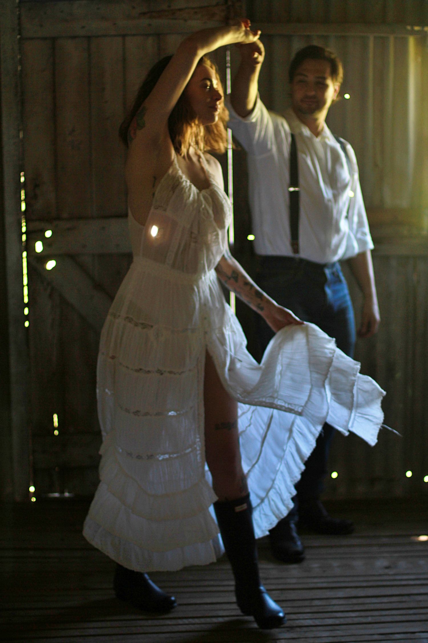 Romantic engagement photos of a couple dancing together inside a rustic barn