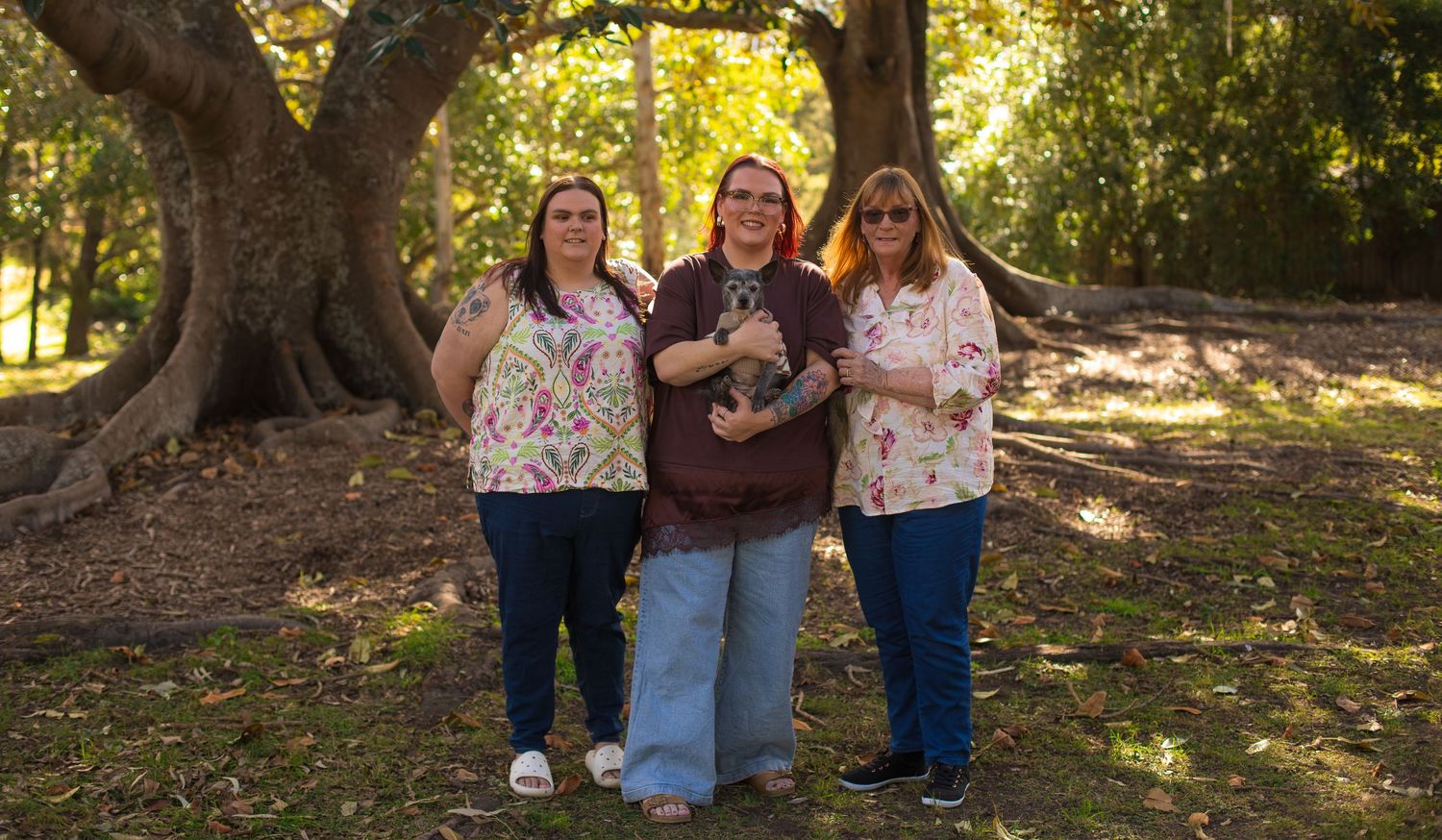 Three generations of women standing together with a young child during an extended family photography session.