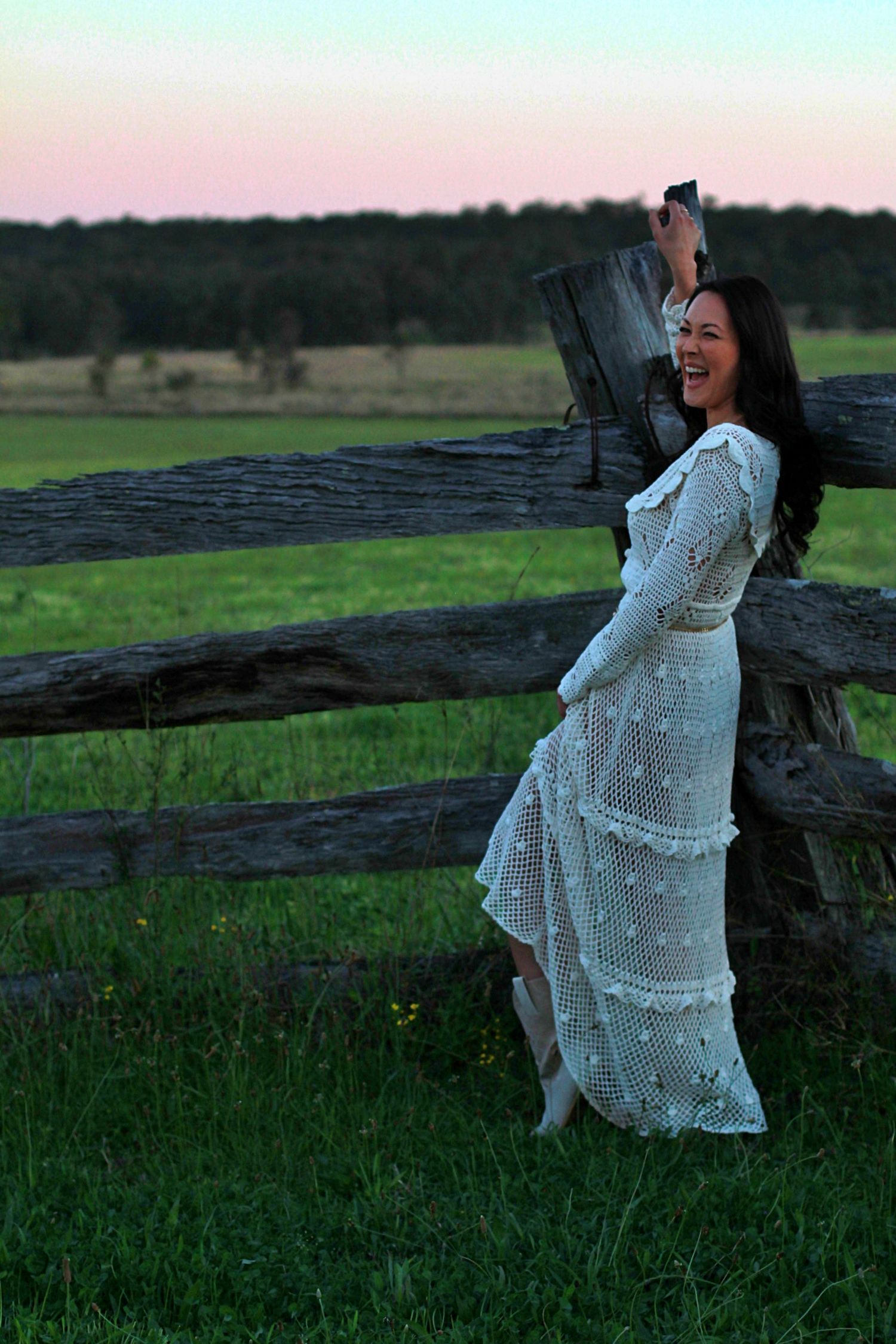 Fun outdoor portrait of a woman leaning on a fence looking away