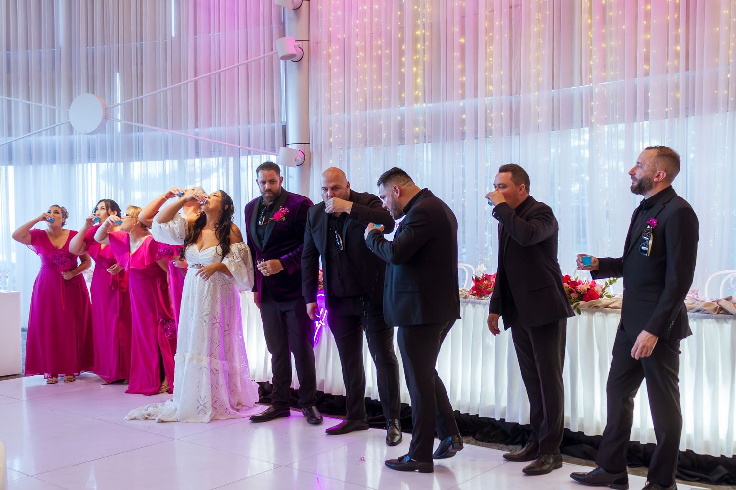 Bridal party taking shots on their grand reception entrance, fun wedding celebration moment.