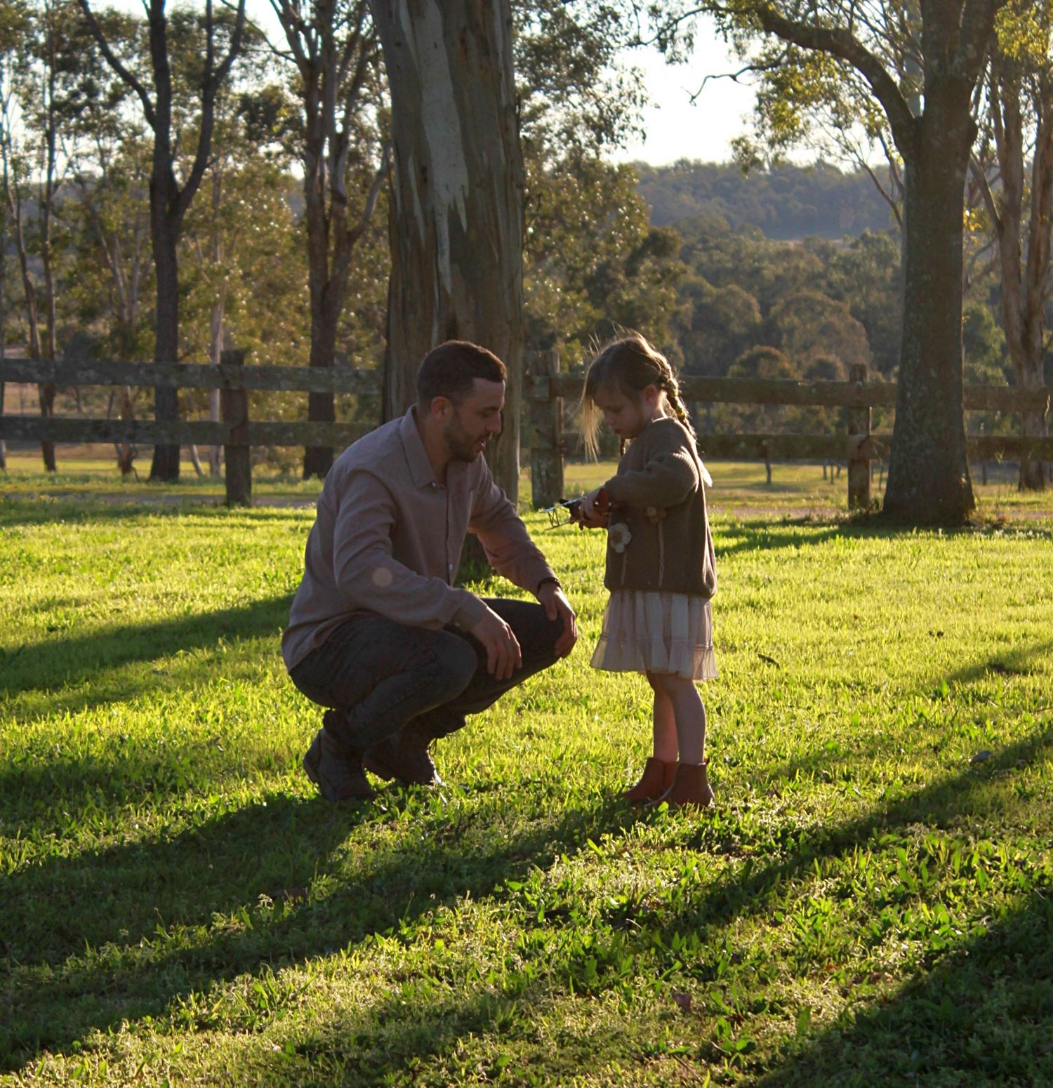 Close up of child smiling next to her an adult outdoors during a family session