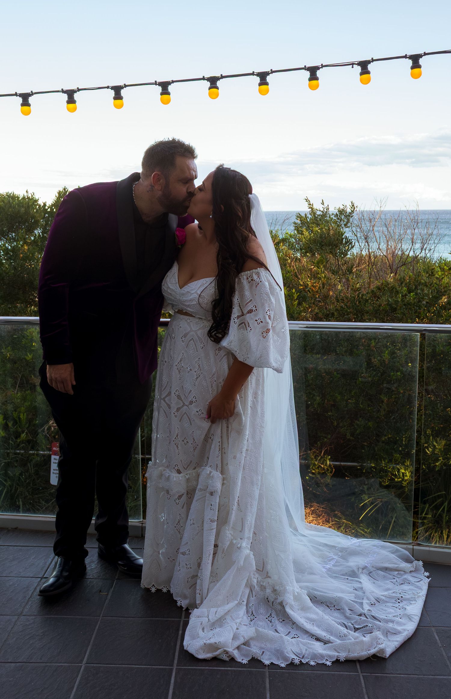 Bride and groom kissing on balcony during wedding portraits.