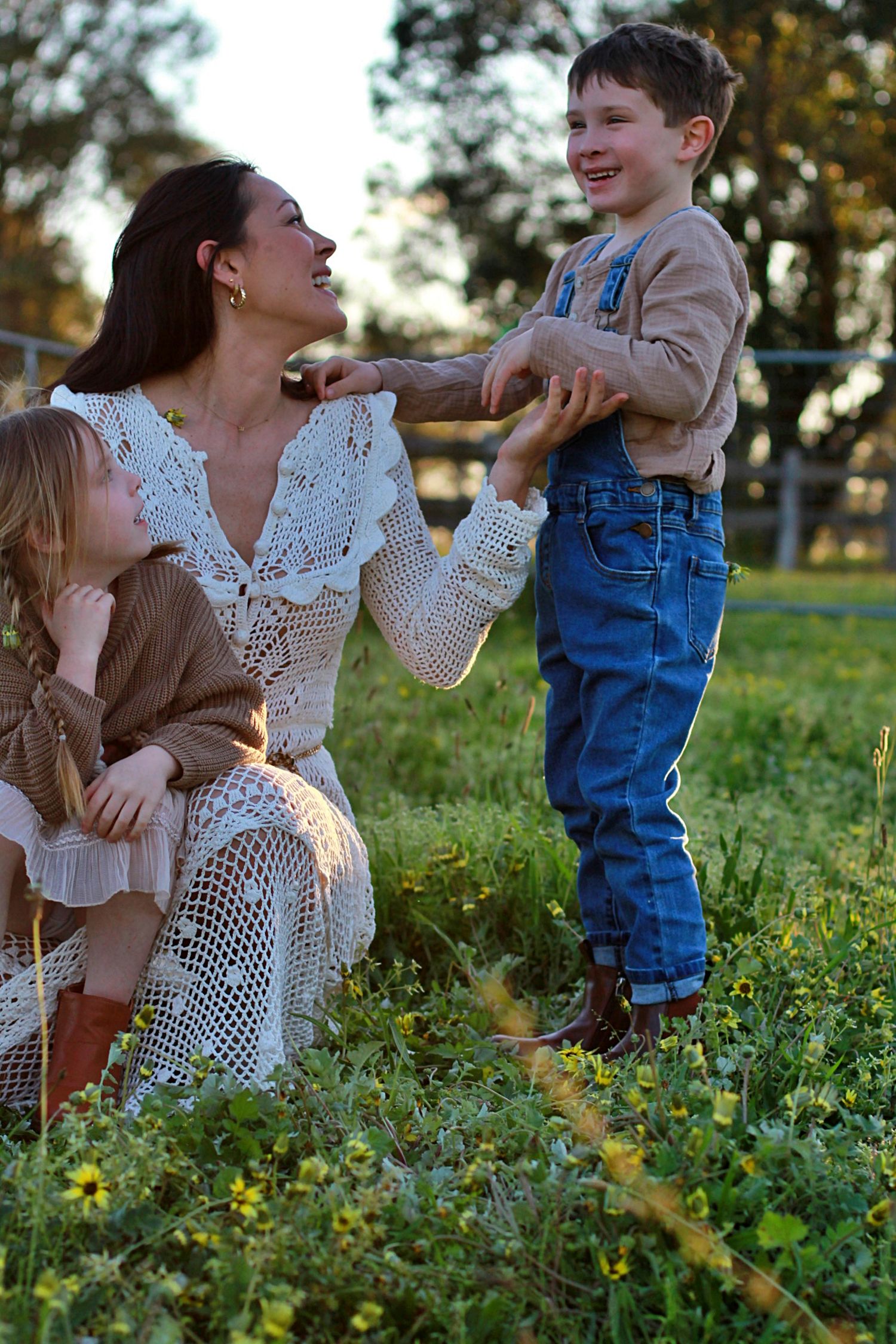 Playful family photo of mum and children sitting together outdoors during a family session
