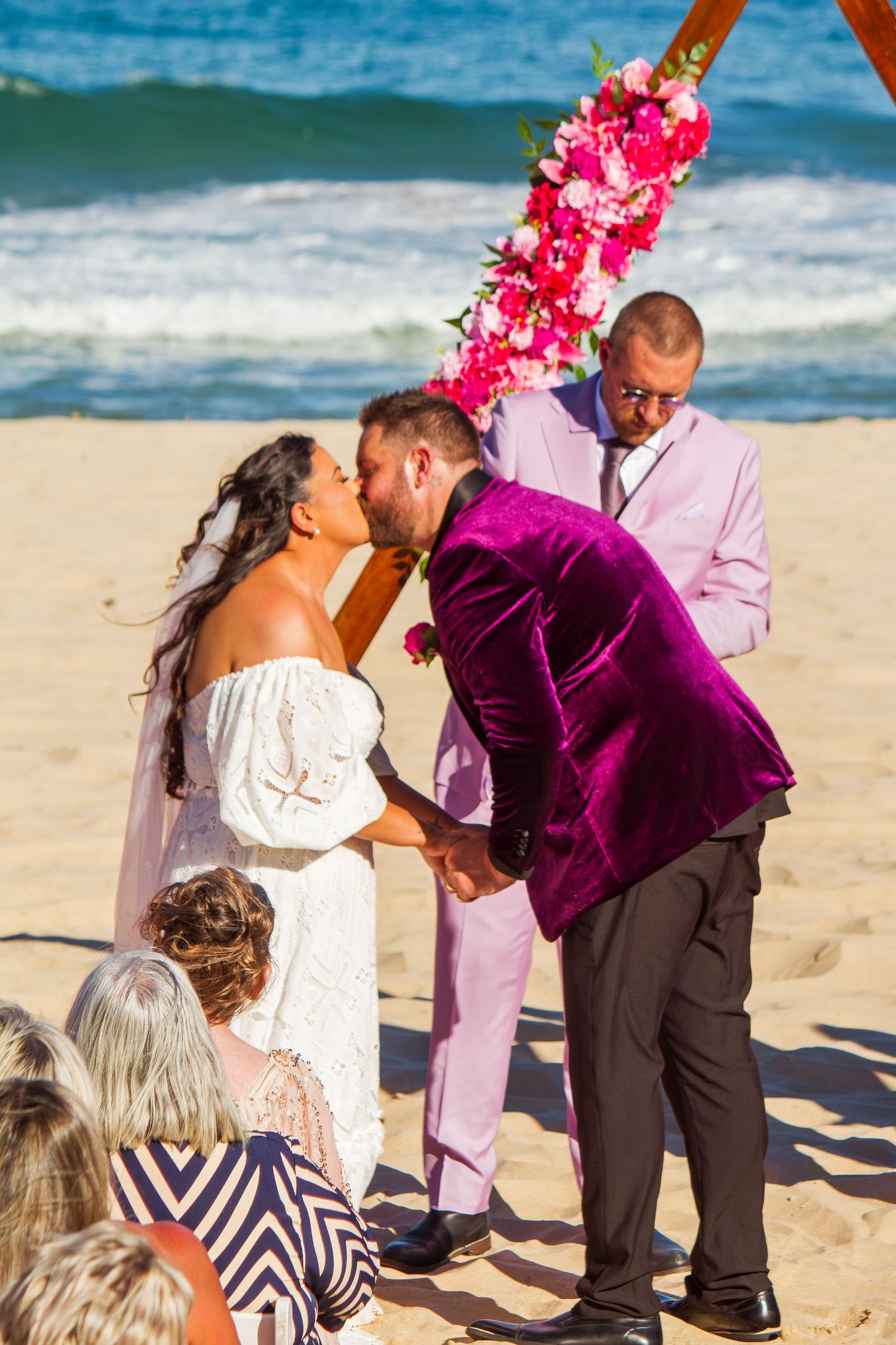 Bride and groom sharing their first kiss as newlyweds during their beach wedding ceremony.
