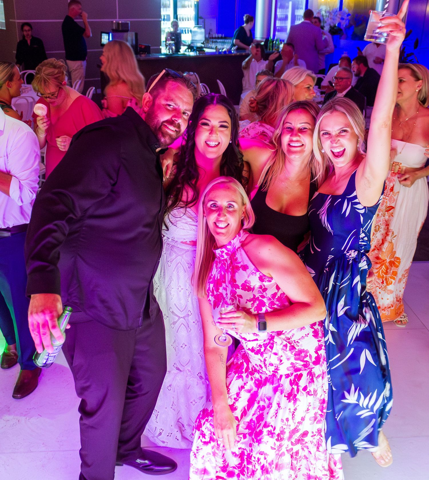 Candid fun portrait of guests with the bride and groom on the dance floor, capturing joyful moments at their wedding celebration.