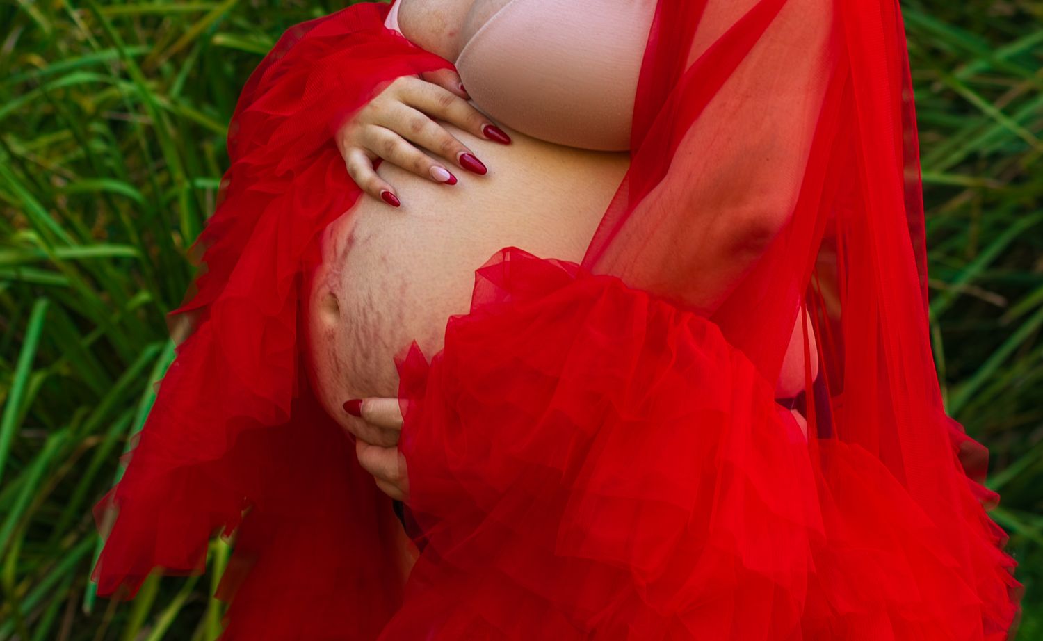 Intimate close-up of a mom cradling her baby bump during a maternity session.