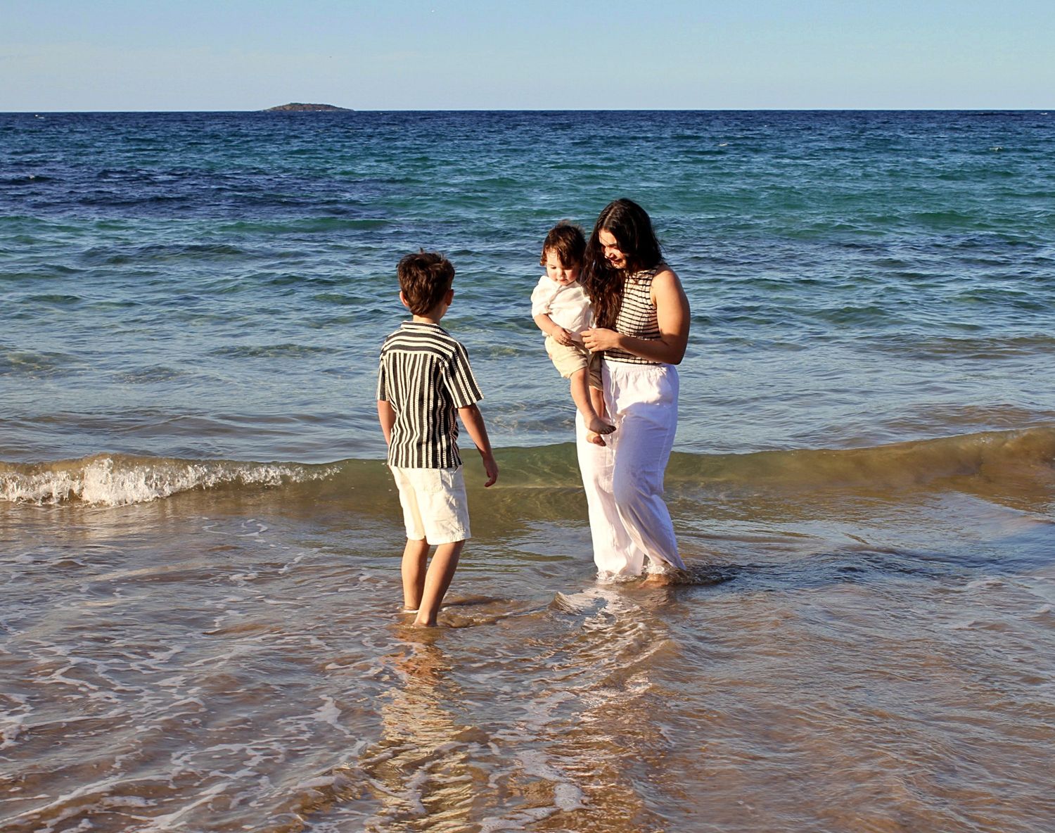 Mother and sons sharing a playful moment in the water during a motherhood session.