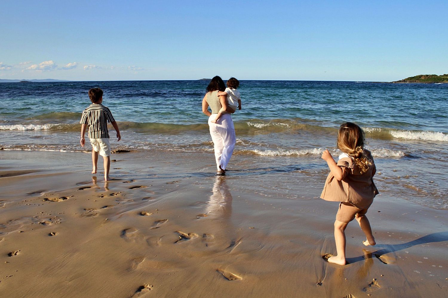 Authentic motherhood moment of a mother and her children connecting through play by the sea.