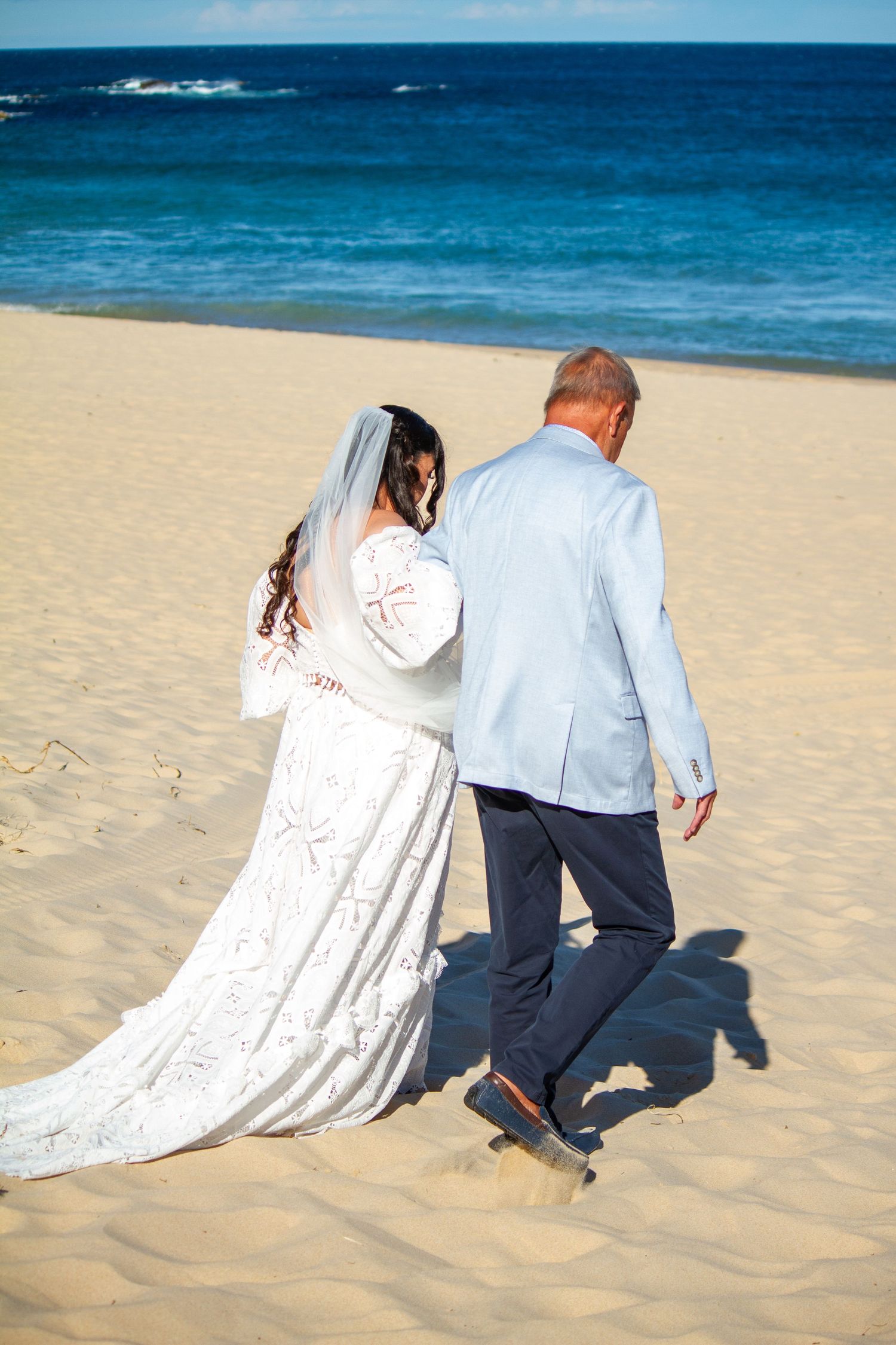 Father walking bride down the aisle during beach wedding ceremony