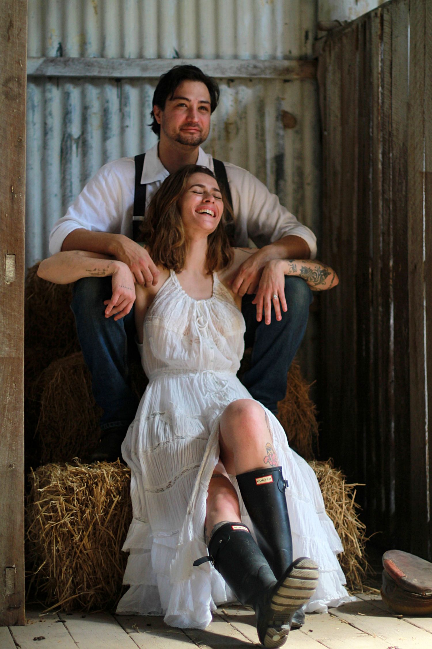 Cozy barn engagement portraits with hay bales and warm country charm