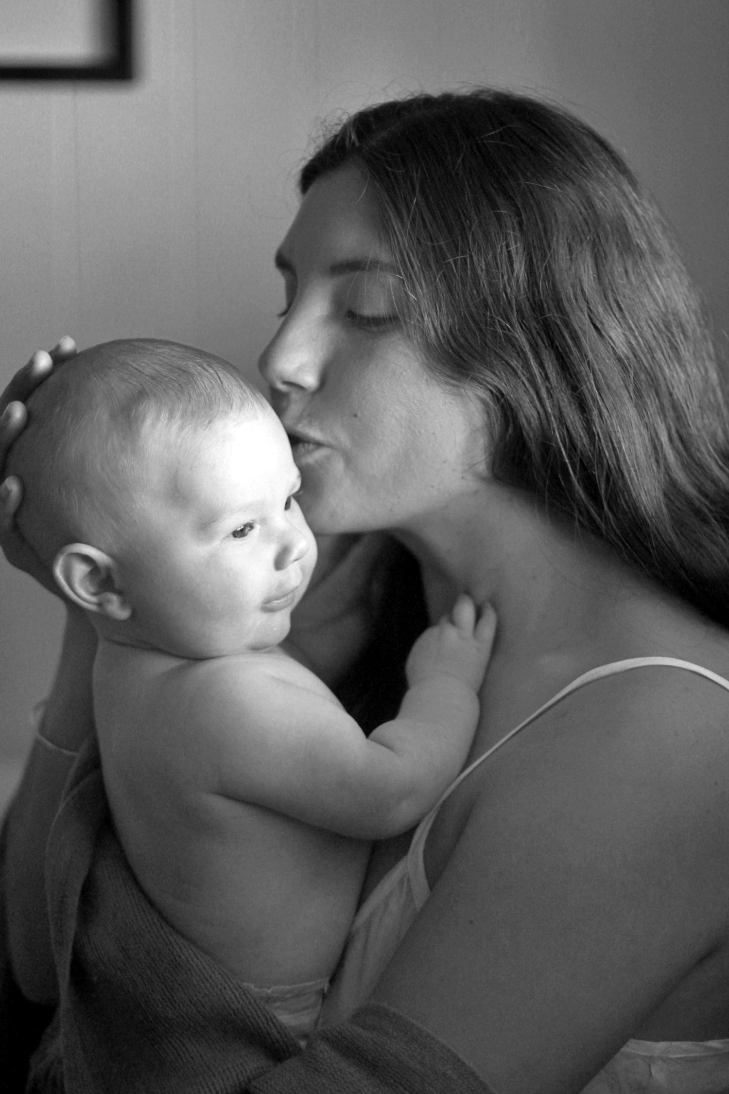 Black and white portrait of mum kissing her newborn baby during a lifestyle motherhood session by A Lasting Impression Photography.