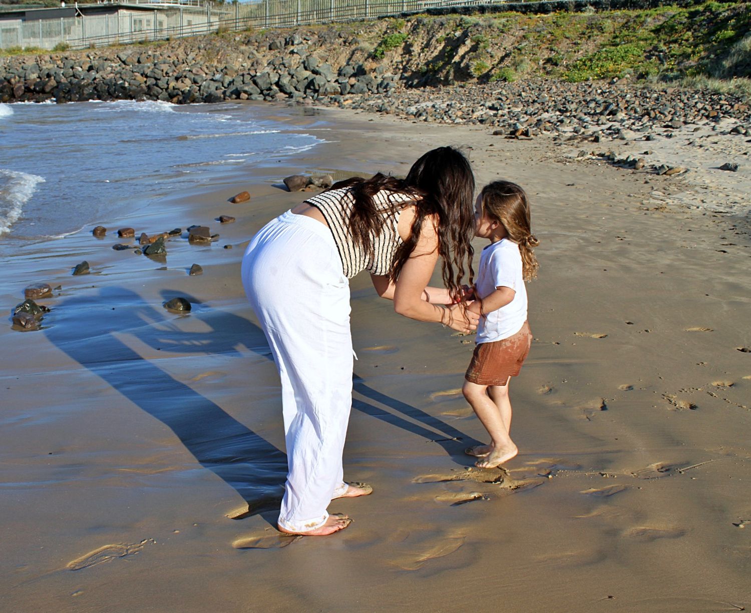 Mum comforting her son on the beach during a motherhood session.