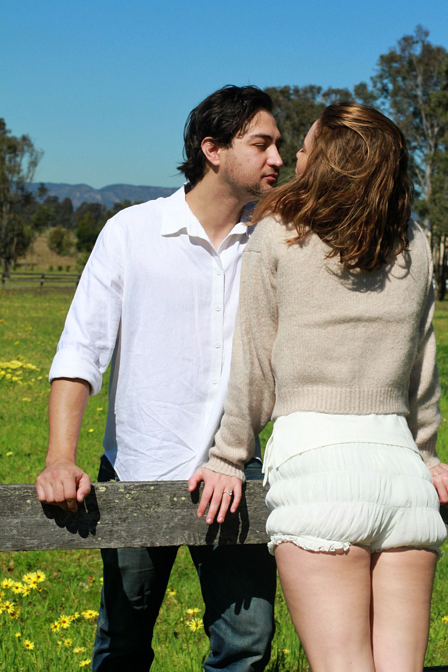 Engagement session in a grassy field during golden hour light