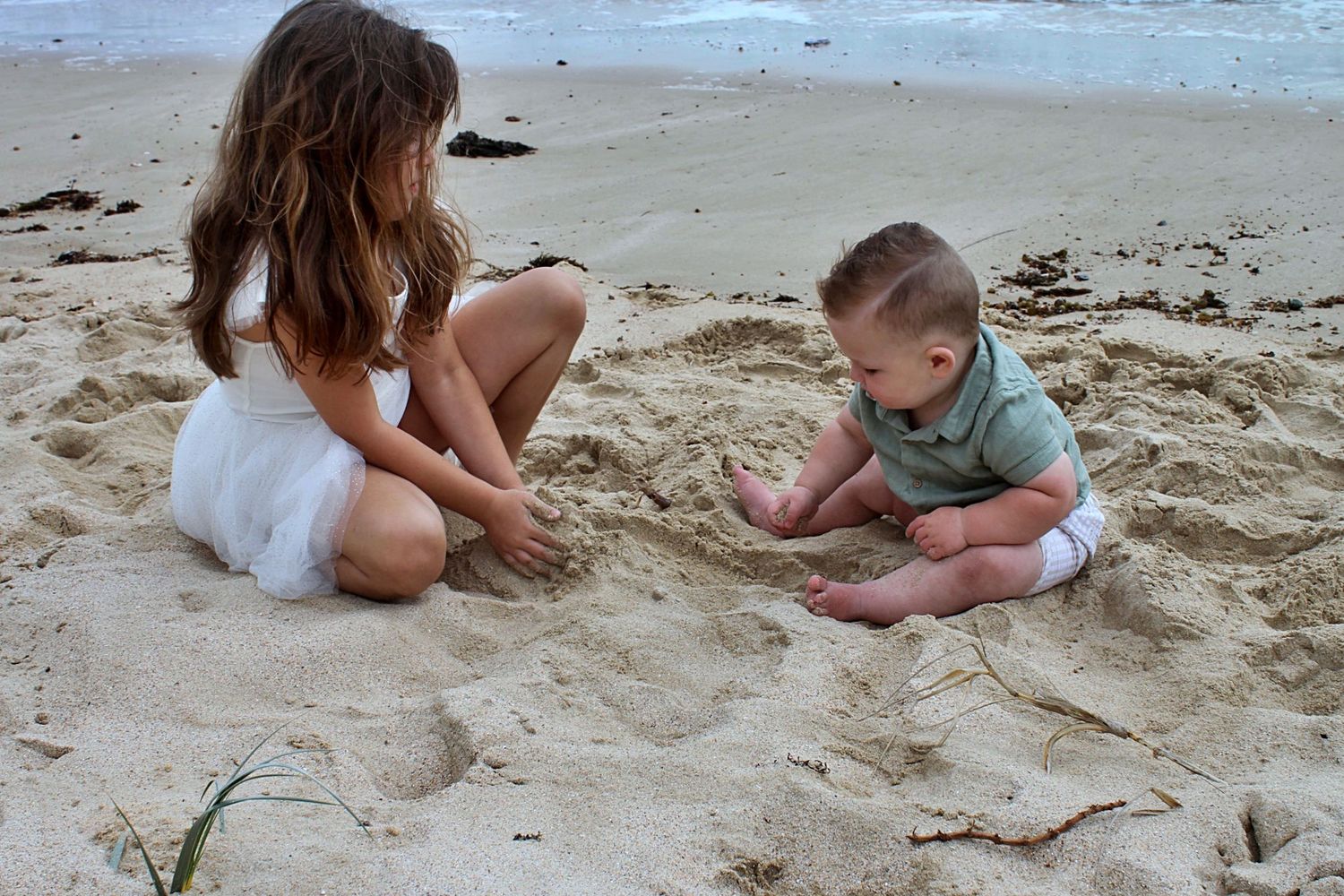 Brother and sister playing together in the sand on the beach in the Illawarra, capturing joyful sibling connection.