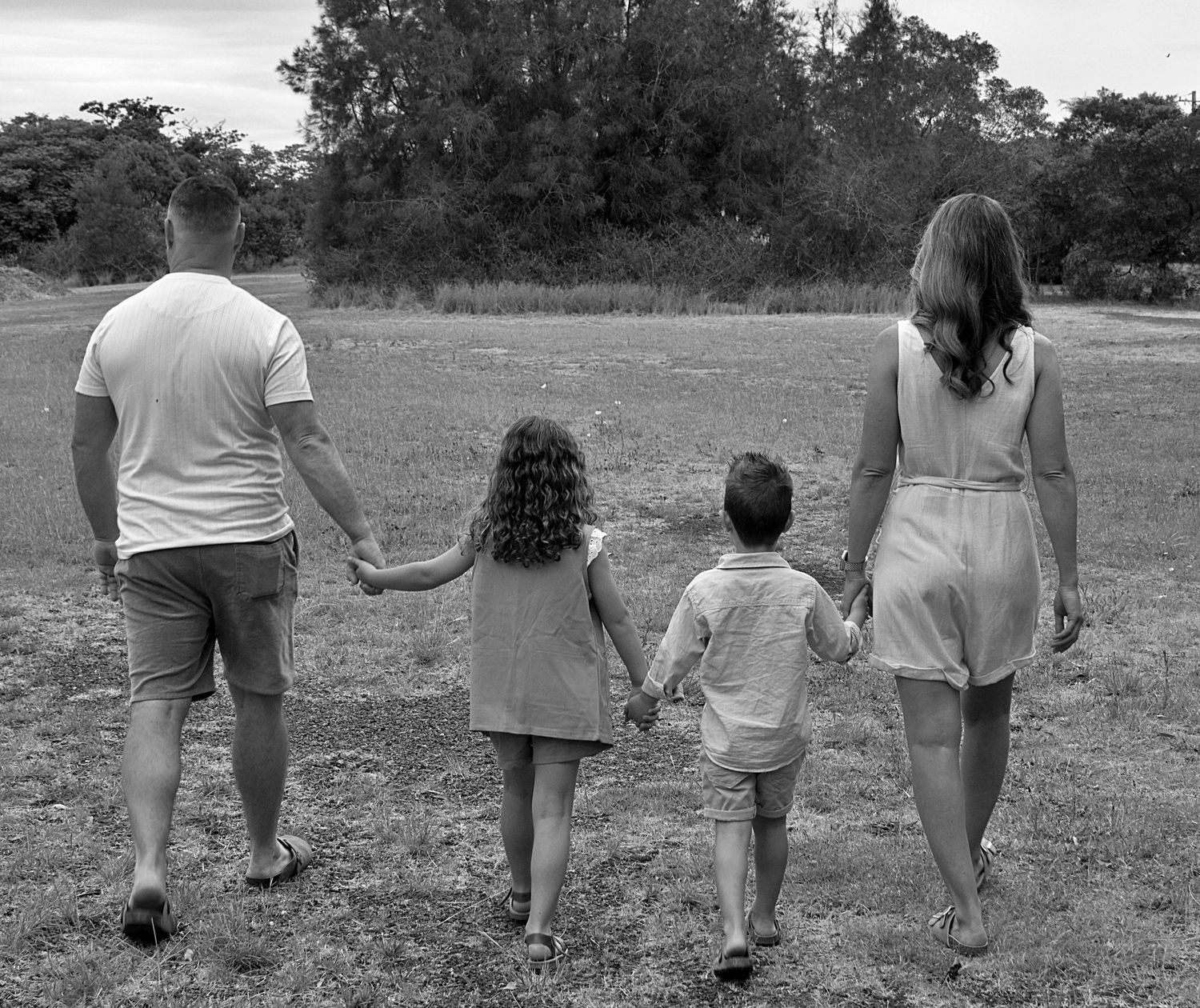 Natural family photography session in Dapto featuring a timeless black and white portrait of parents and children walking hand in hand.