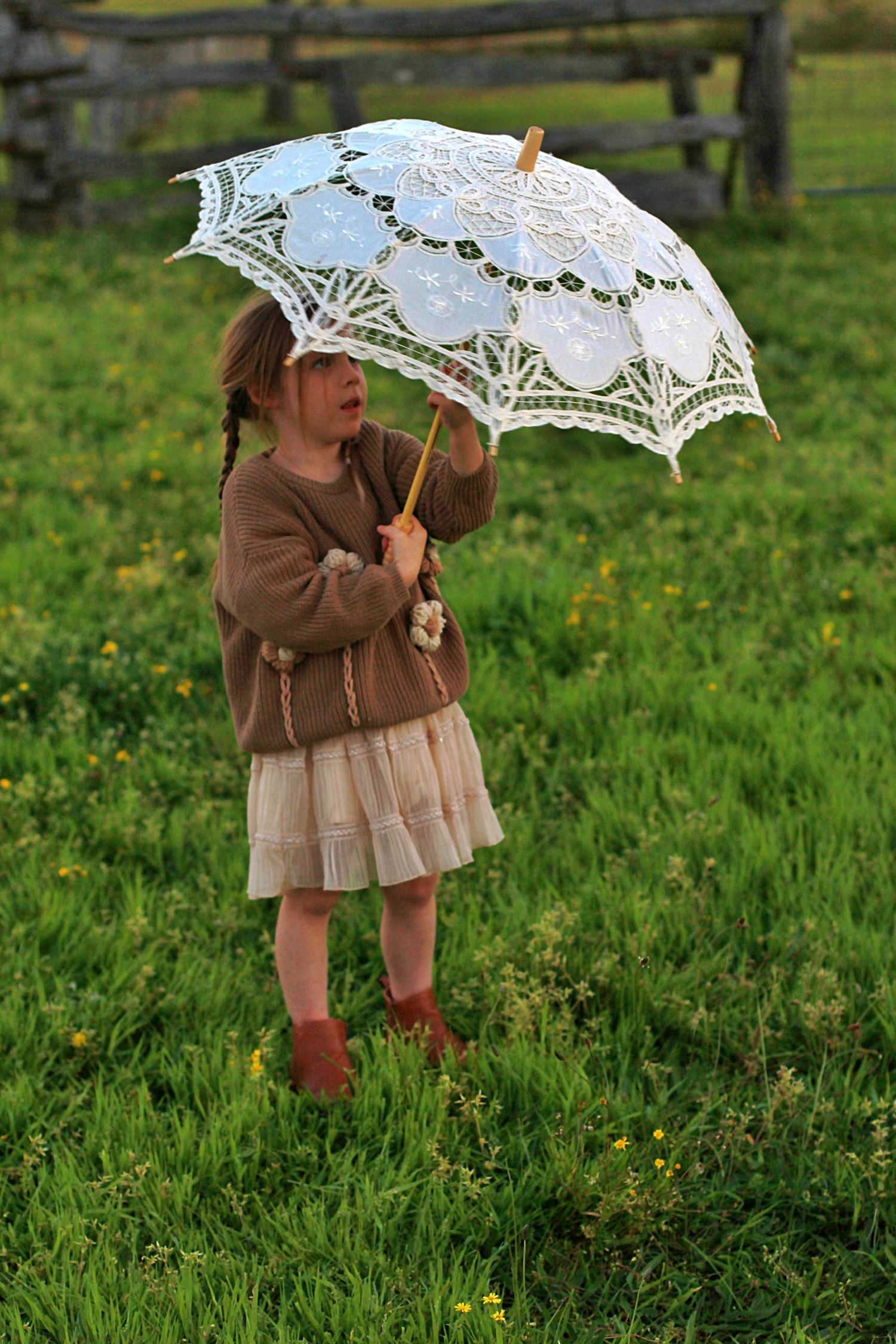 Little girl holding a parasol, captured in a candid moment during a lifestyle family photography session.