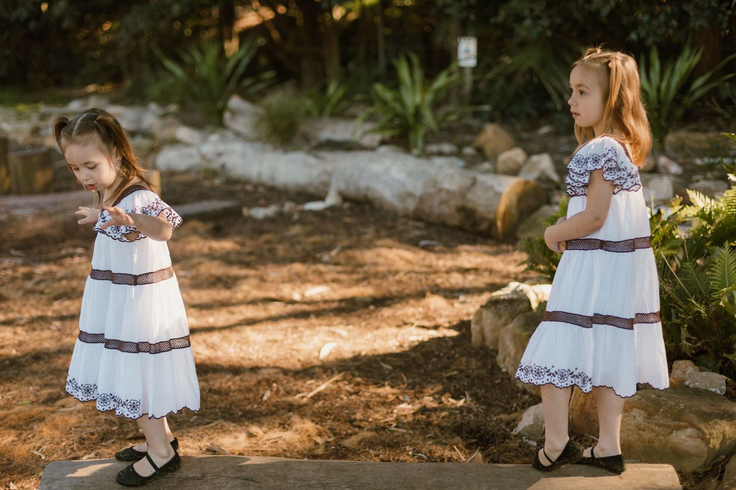 Two young sisters exploring and playing together during a relaxed outdoor family photography session.