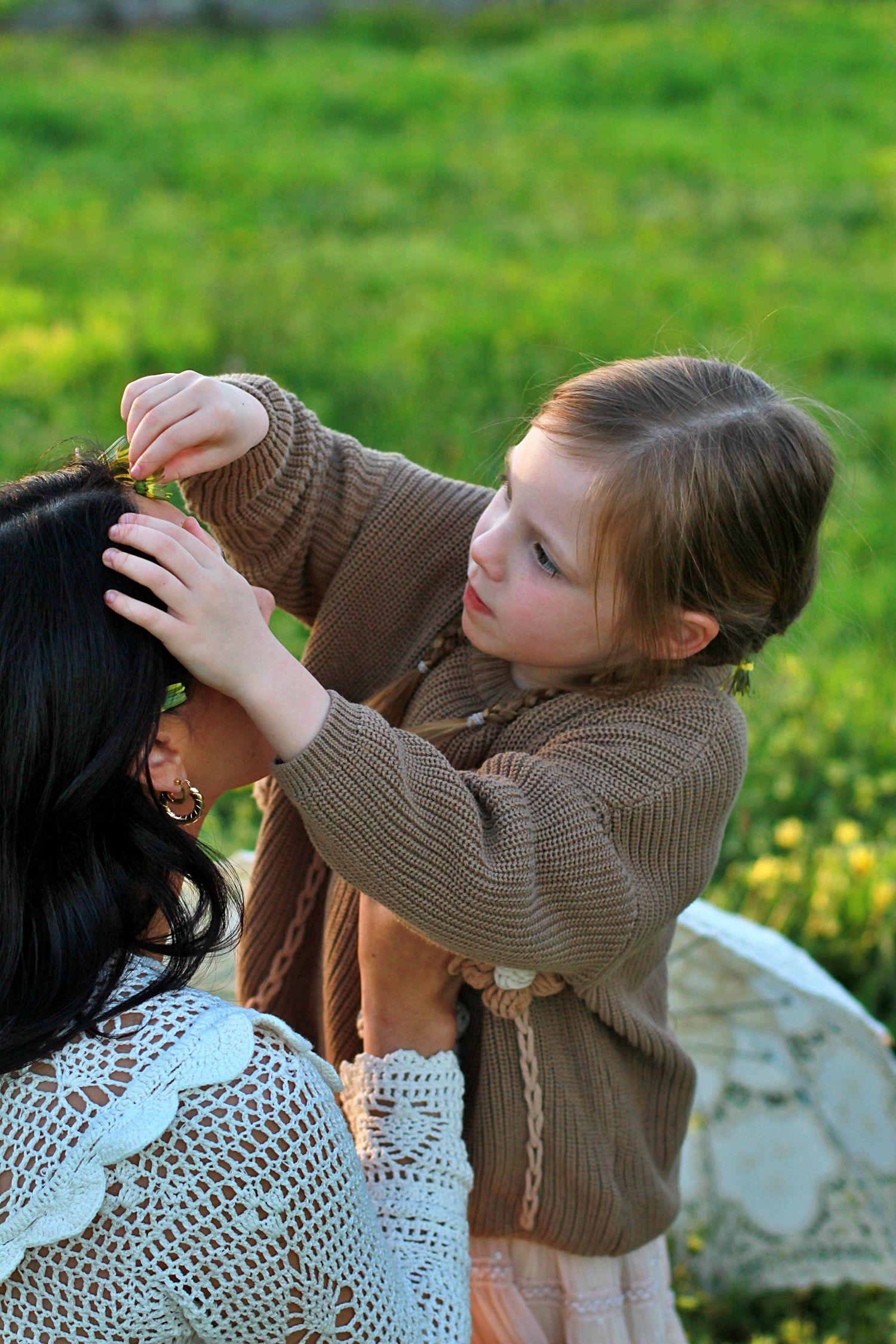 Sweet moment of daughter decorating mum’s hair with flowers during a family session