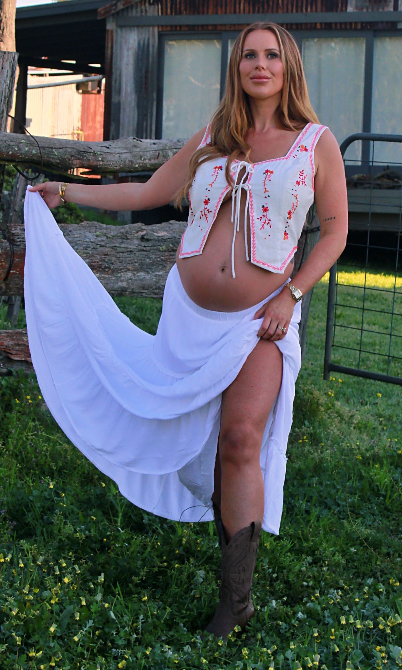 Calm maternity portrait of a mumma to be holding her skirt in an open field.