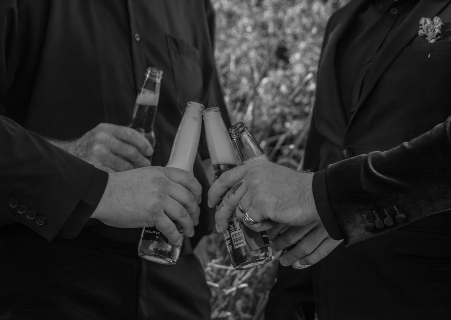 Groom and groomsmen cheering drinks after wedding ceremony.
