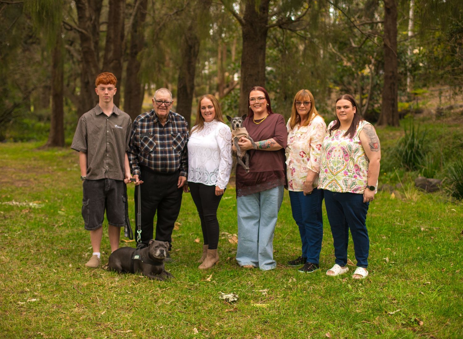 Extended family standing together with their puppos during an outdoor family photography session in the Illawarra.
