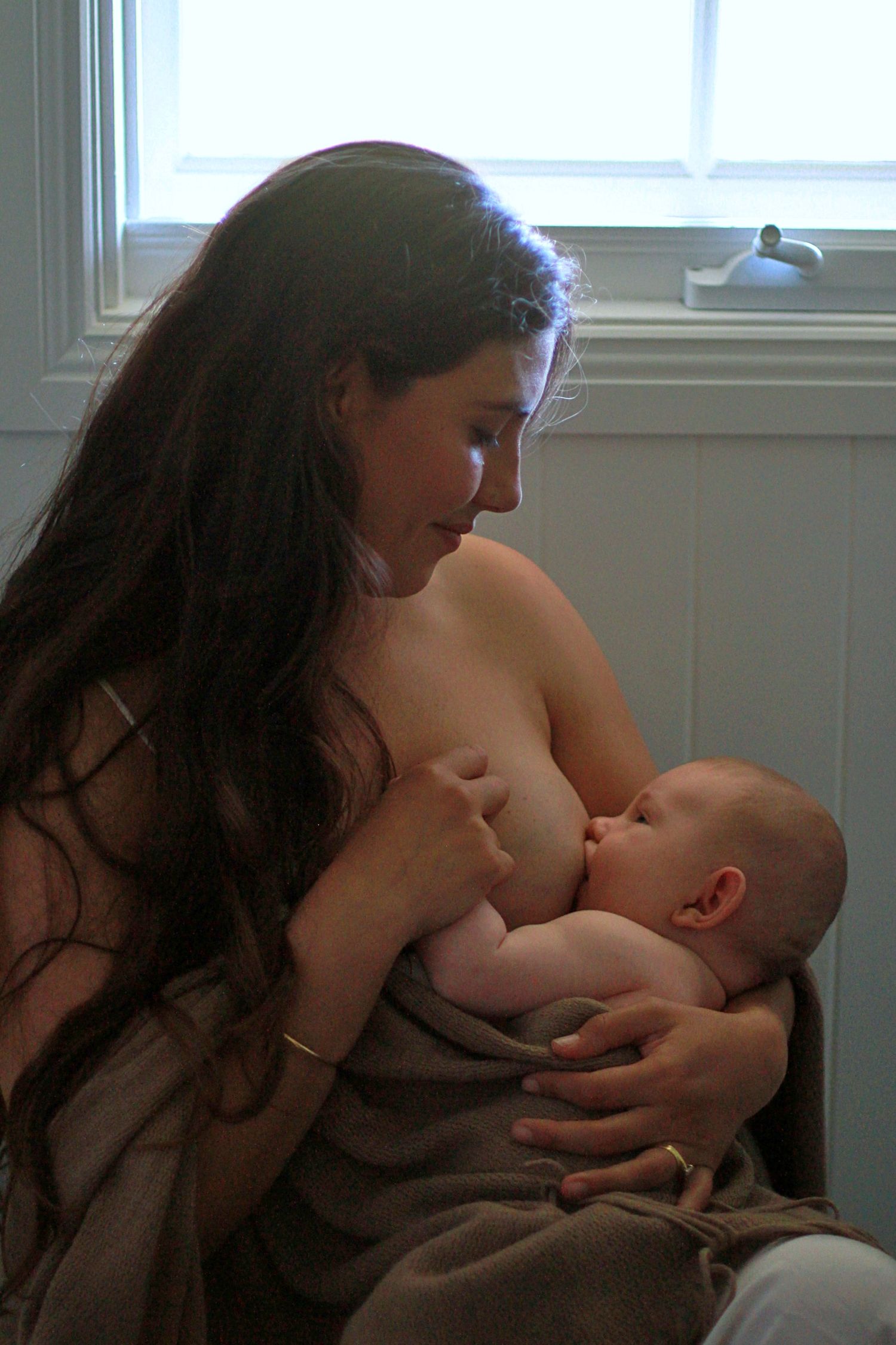 Mother breastfeeding her baby during a natural lifestyle motherhood session at home by A Lasting Impression Photography.