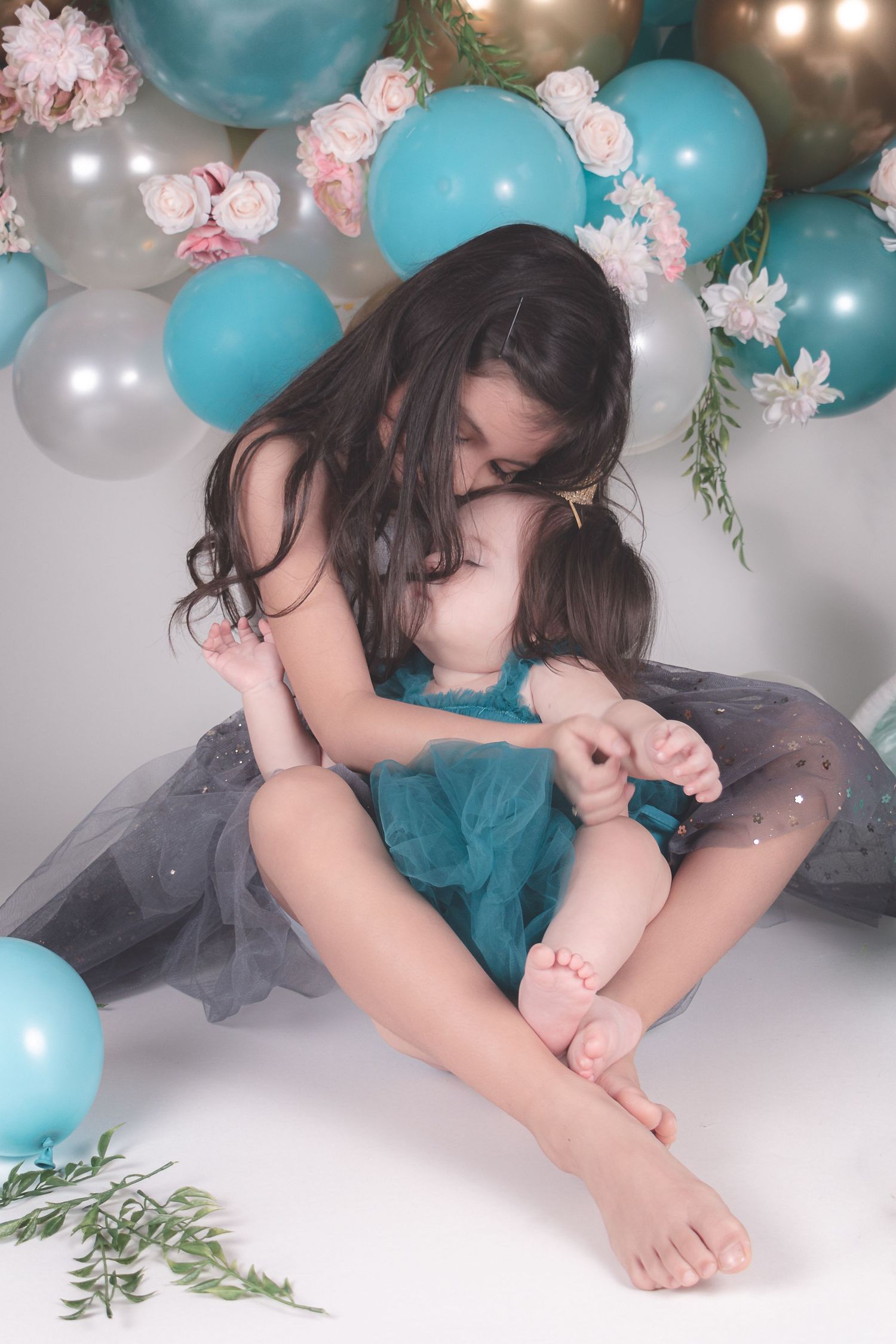 Dreamy portrait setup with teal and gold balloons, flowers, and tulle decorations.