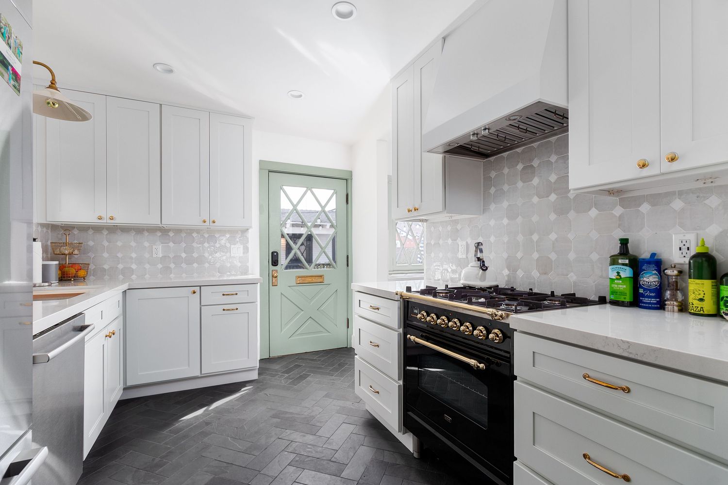 Modern white kitchen with subway tile backsplash, stainless appliances, and brass hardware accents.