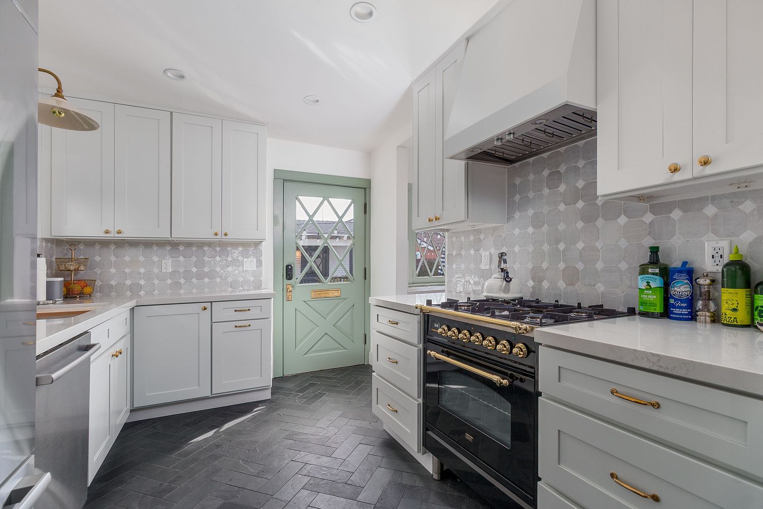 Contemporary kitchen featuring white cabinetry, stainless appliances and marble backsplash.