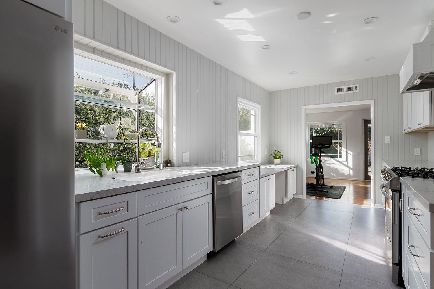 Modern white kitchen with sleek cabinets and recessed lighting extending down a long hallway.
